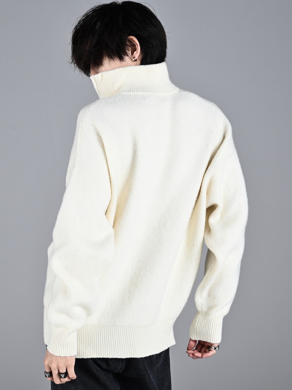 ホワイト系のスニーカー、ホワイト系のニット/セーター、ブラック系のデニムパンツを着用したメンズの秋コーディネートの4枚目の写真