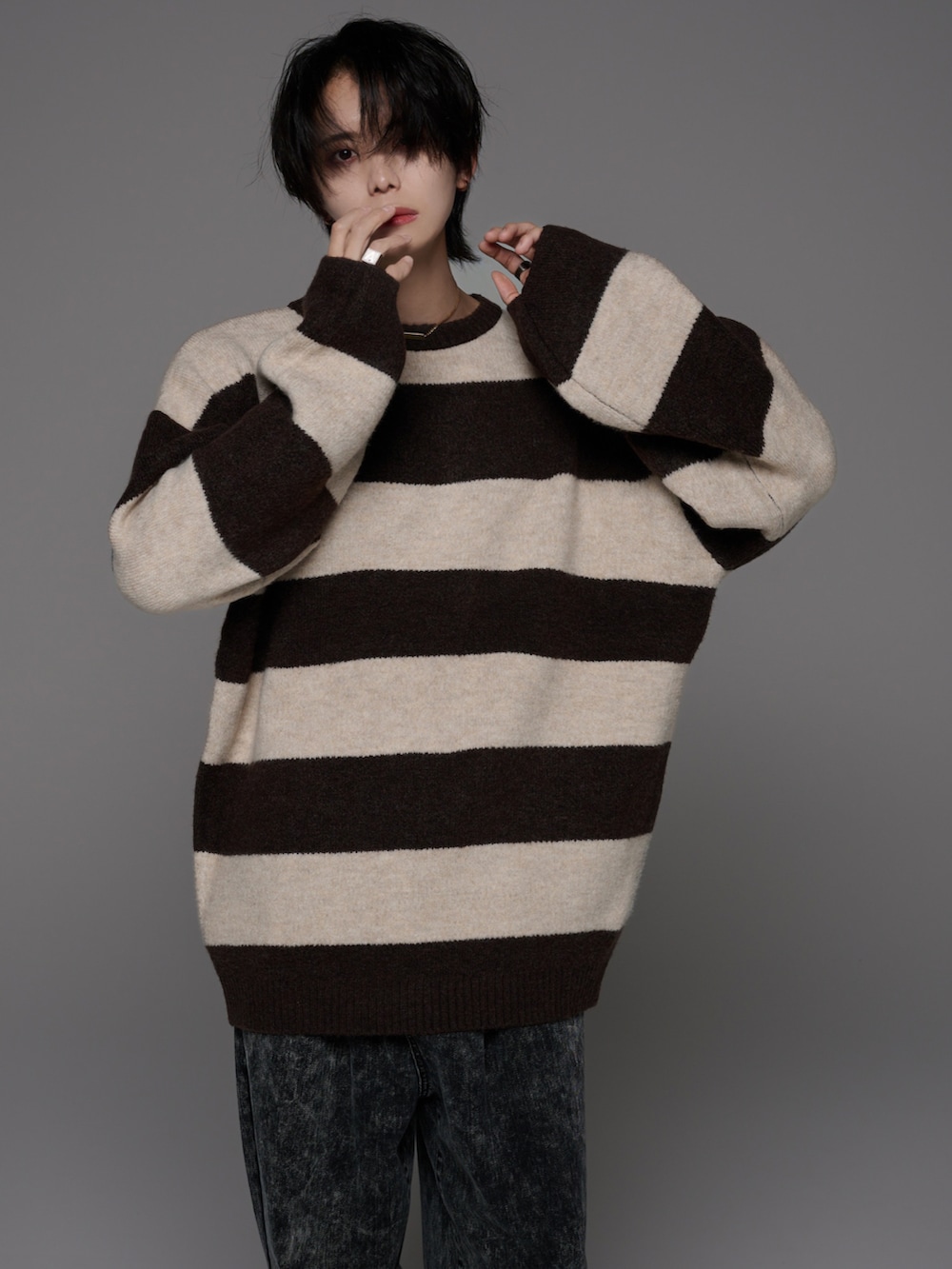 ブラック系のデニムパンツ、ホワイト系のスニーカー、ブラウン系のニット/セーターを着用したメンズの秋コーディネートの3枚目の写真