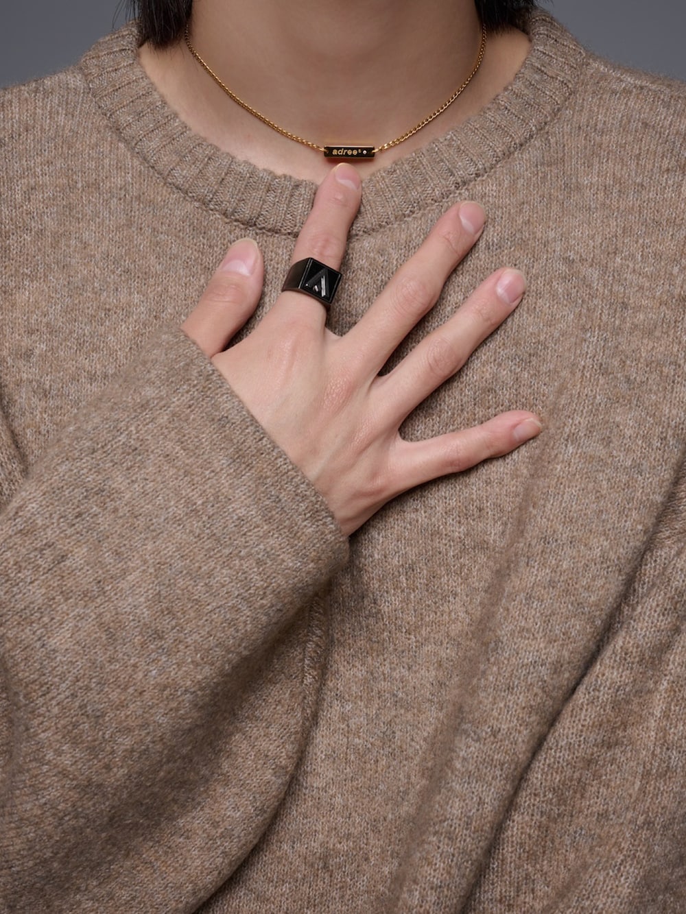 ブラウン系のスラックス、ブラック系のスニーカー、ベージュ系のニット/セーターを着用したメンズの秋コーディネートの2枚目の写真