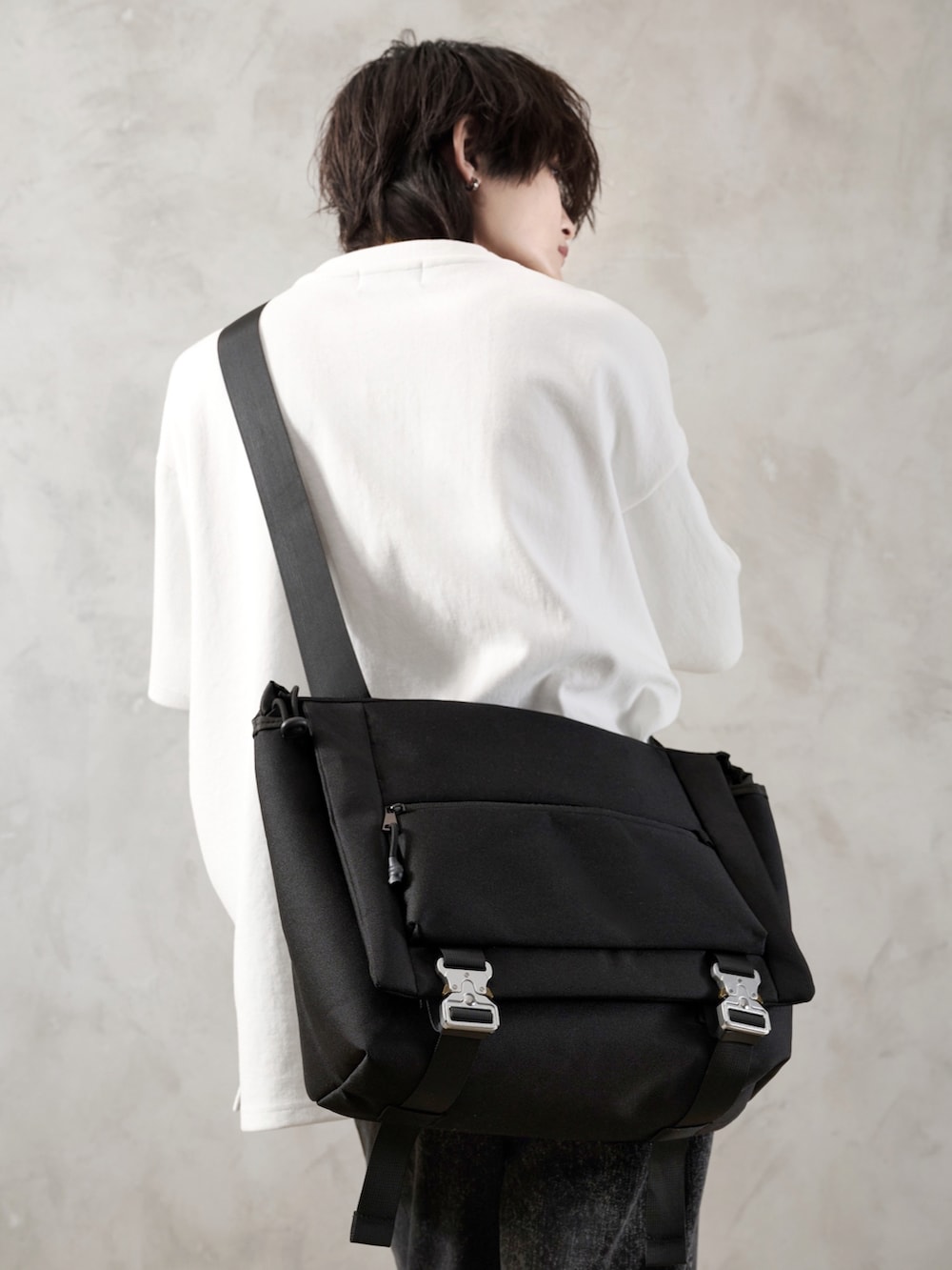 ブラック系のデニムパンツ、ホワイト系のTシャツ/カットソー、ブラック系のショルダーバッグを着用したメンズの春コーディネートの5枚目の写真