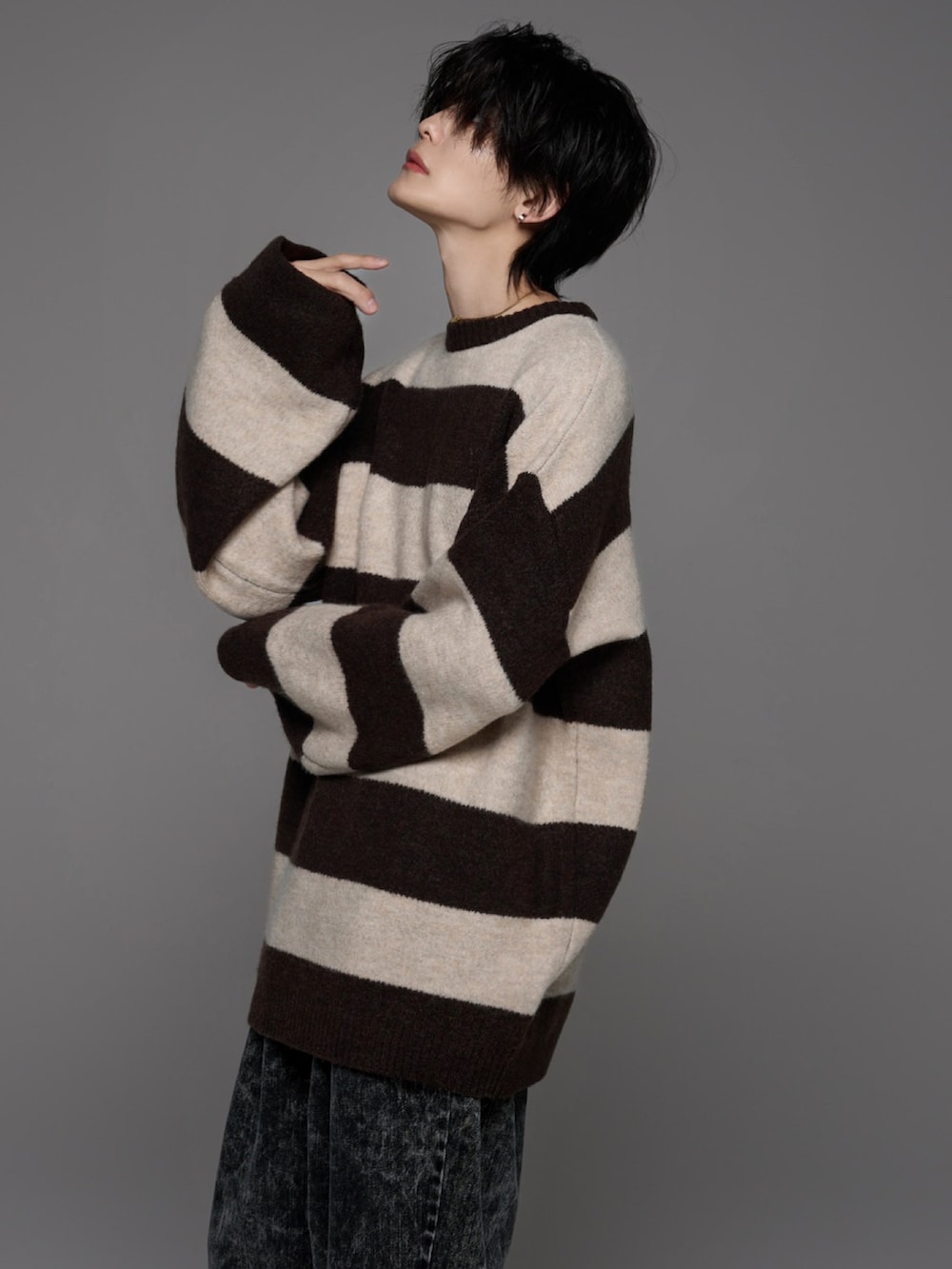 ブラック系のデニムパンツ、ホワイト系のスニーカー、ブラウン系のニット/セーターを着用したメンズの秋コーディネートの4枚目の写真