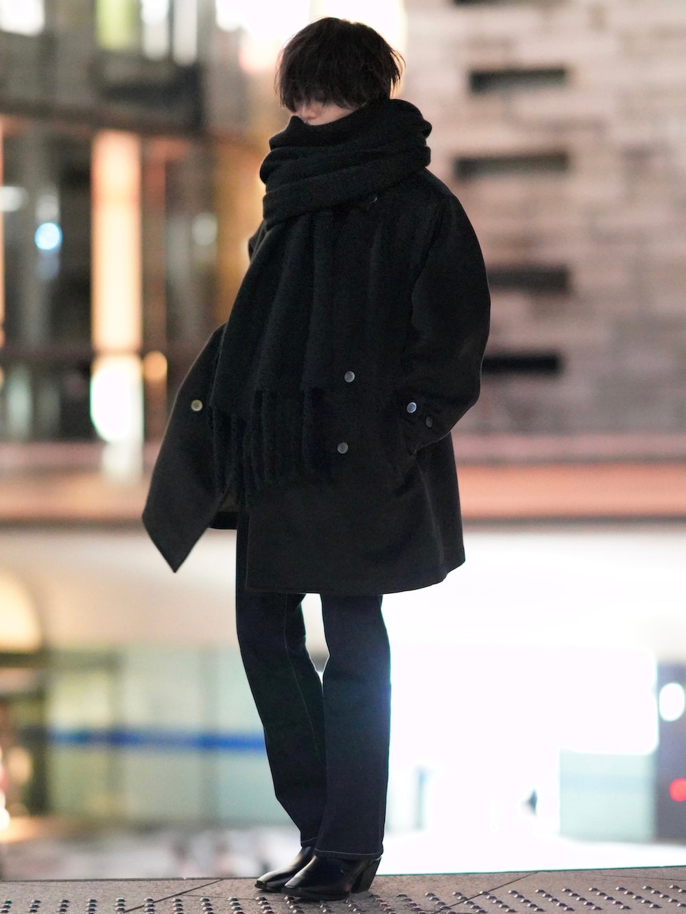 レッド系のニット/セーター、ブルー系のデニムパンツ、ブラック系のブーツを着用したメンズの秋コーディネートの4枚目の写真