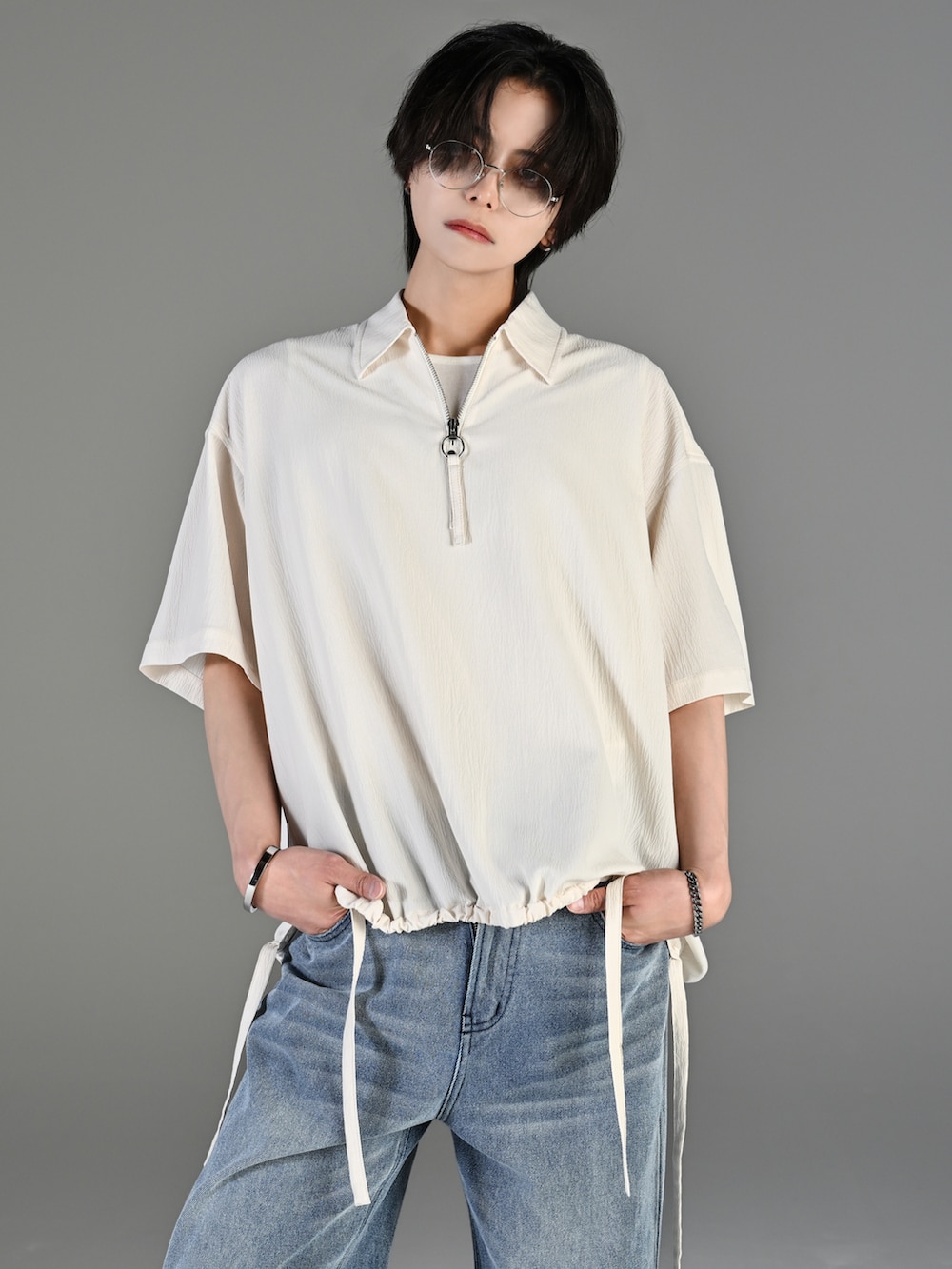 グレー系のタンクトップ、ブルー系のデニムパンツ、ホワイト系のスニーカーを着用したメンズの春コーディネートの2枚目の写真