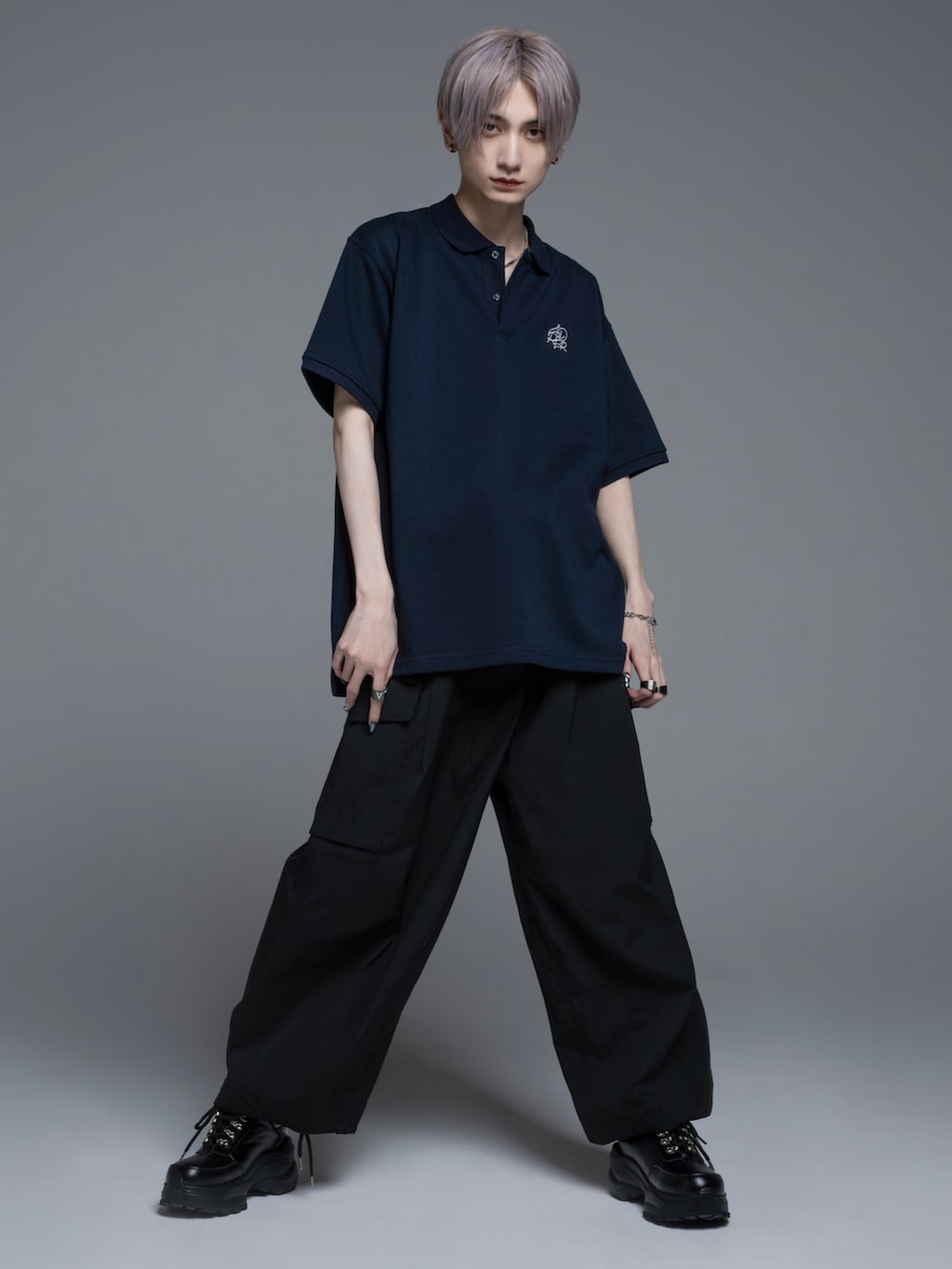 ブラック系のデニムパンツ、ブラック系のブーツ、ホワイト系のポロシャツを着用したメンズの春コーディネートの3枚目の写真