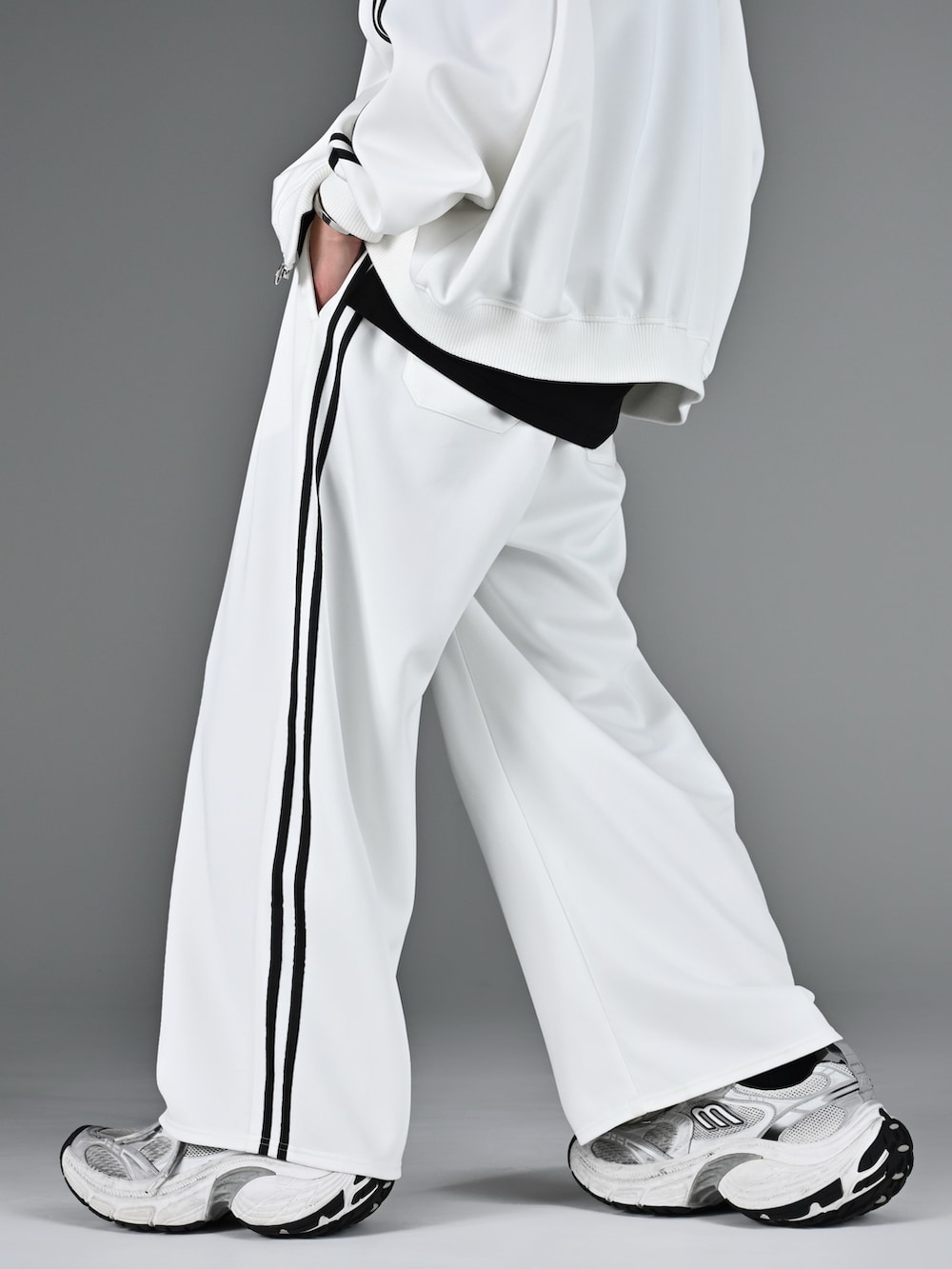 レッド系のタンクトップ、ホワイト系のスニーカー、ホワイト系のブルゾンを着用したメンズの冬コーディネートの2枚目の写真