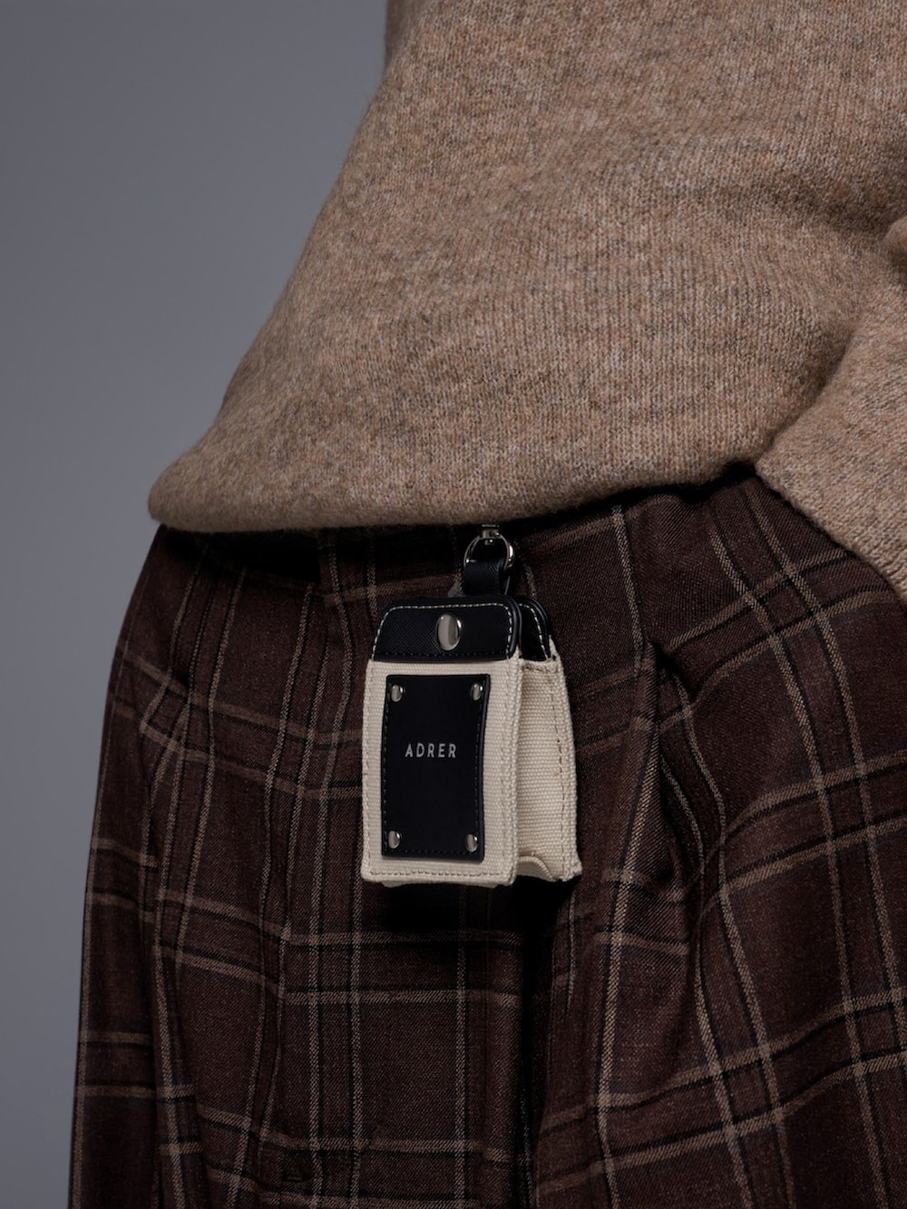 ブラウン系のスラックス、ブラック系のスニーカー、ベージュ系のニット/セーターを着用したメンズの秋コーディネートの4枚目の写真