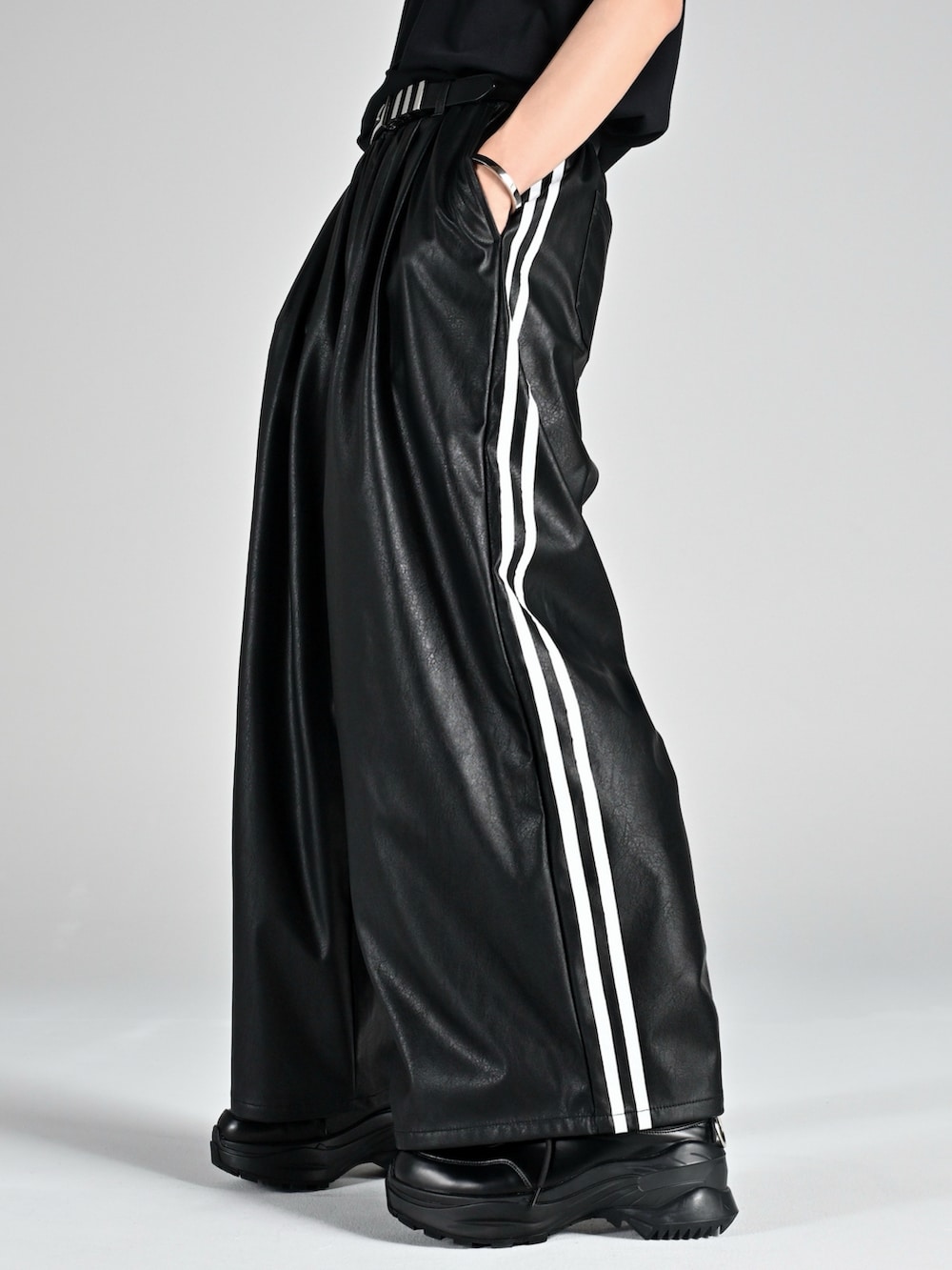 レッド系のタンクトップ、ブラック系のブーツ、ブラック系のブルゾンを着用したメンズの夏コーディネートの3枚目の写真