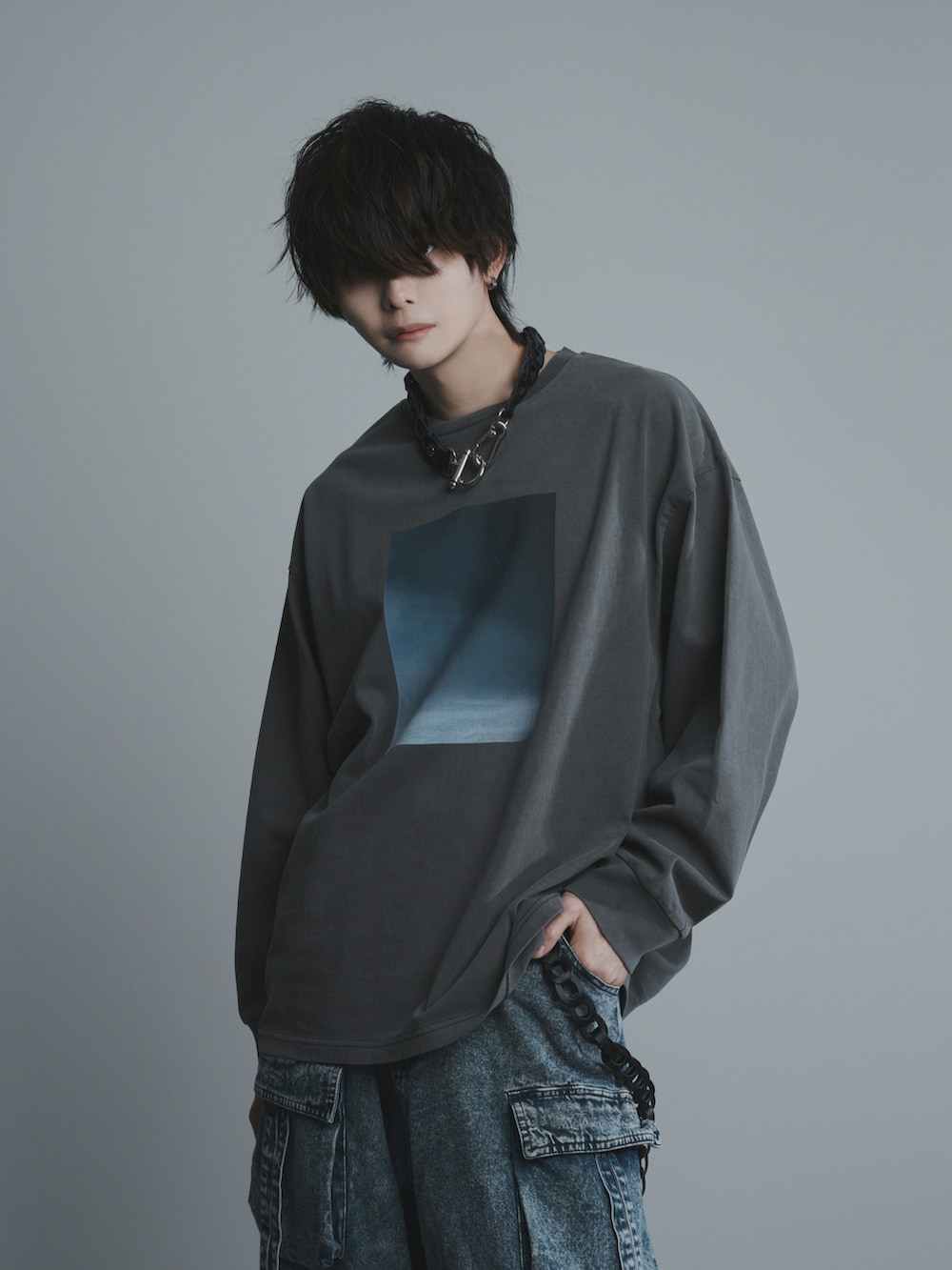 ブルー系のカーゴパンツ、ブラック系のスニーカー、グレー系のTシャツ/カットソーを着用したメンズの冬コーディネートの2枚目の写真