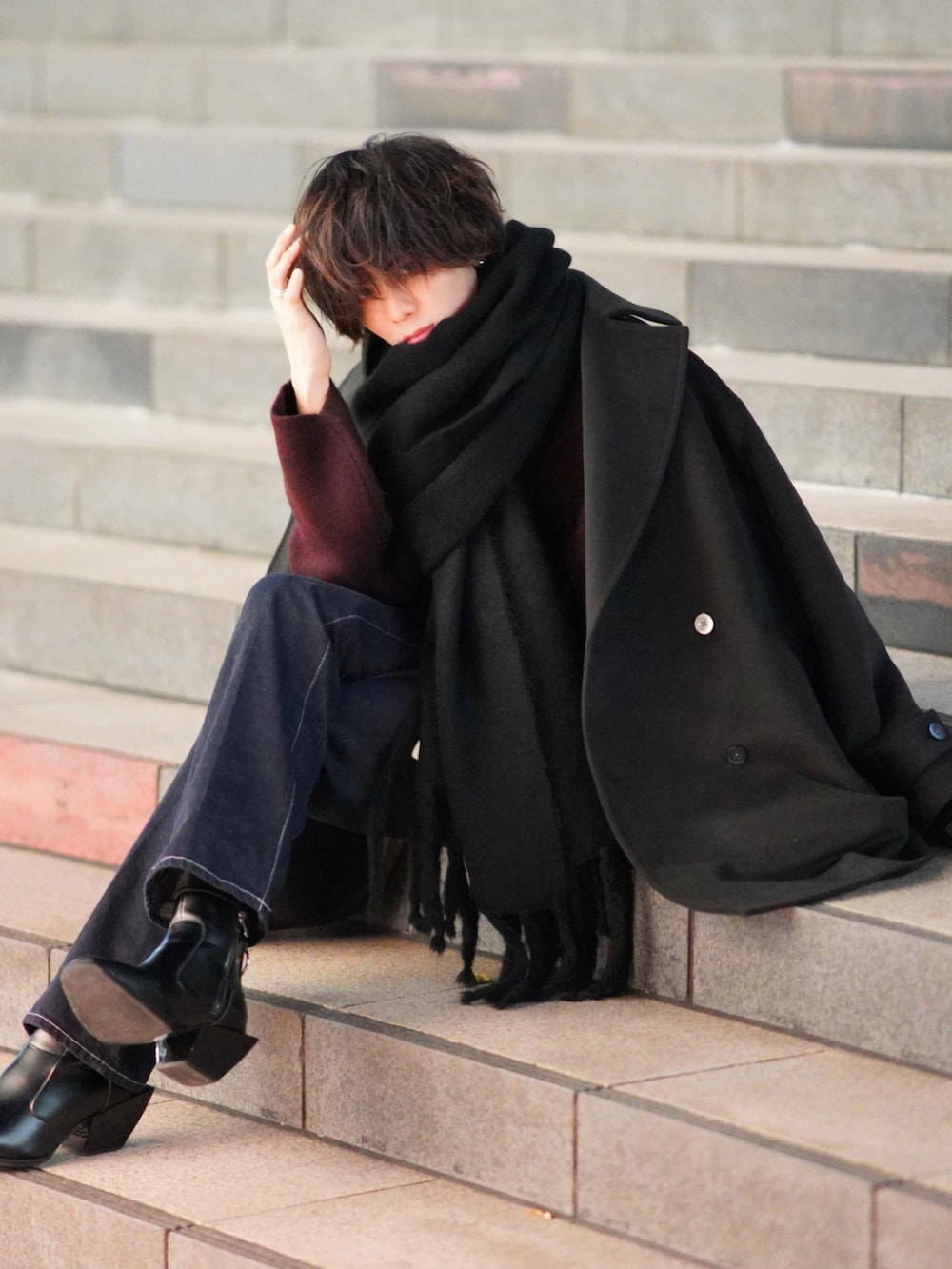 レッド系のニット/セーター、ブルー系のデニムパンツ、ブラック系のブーツを着用したメンズの秋コーディネートの3枚目の写真