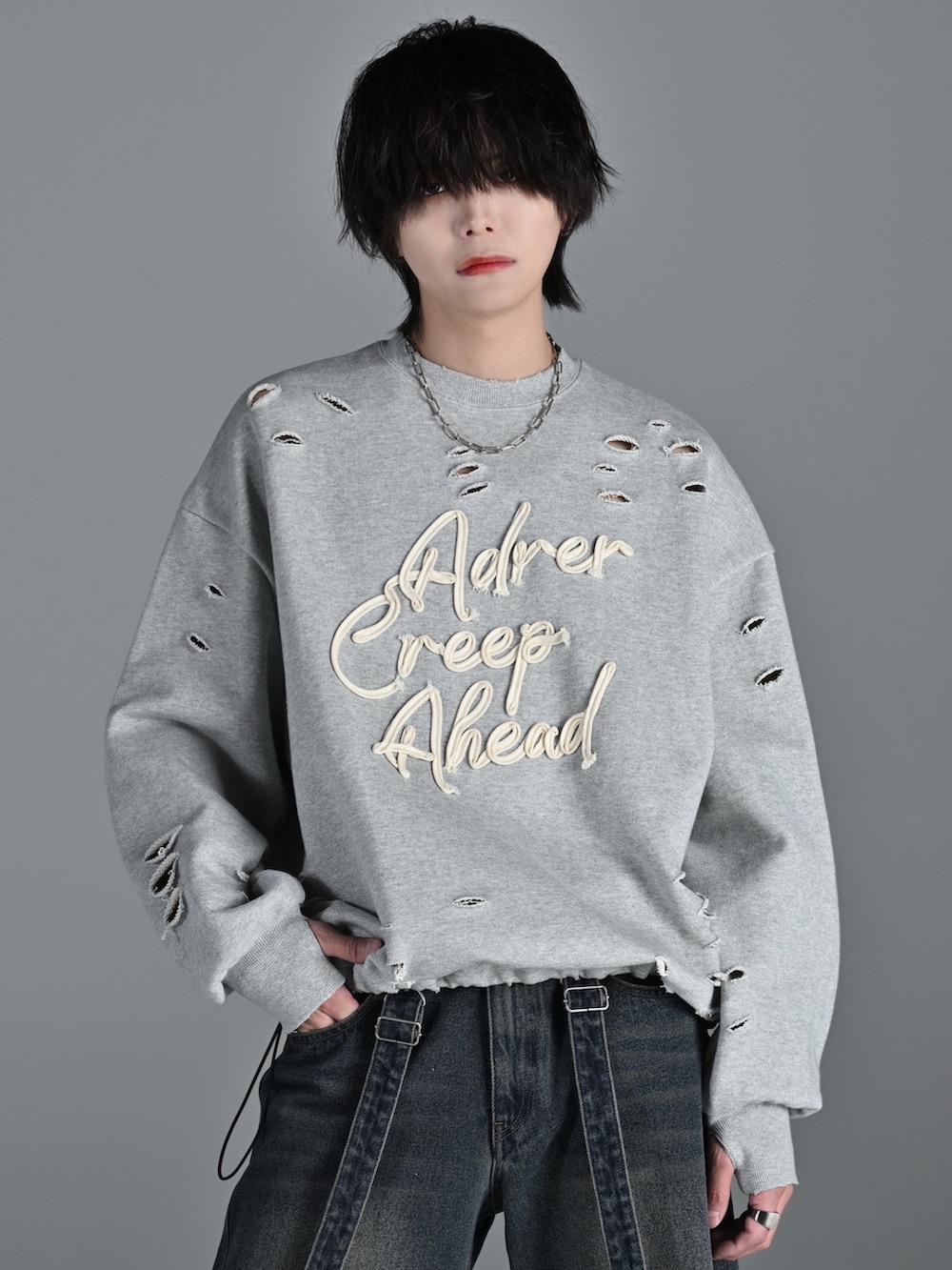 グレー系のスウェット、ブルー系のデニムパンツ、ホワイト系のスニーカーを着用したメンズの冬コーディネートの3枚目の写真