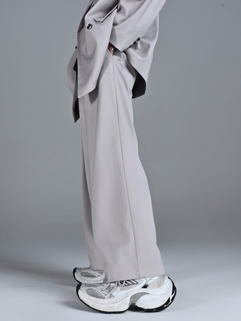 ホワイト系のスニーカー、レッド系のタンクトップ、グレー系のテーラードジャケットを着用したメンズの冬コーディネートの3枚目の写真