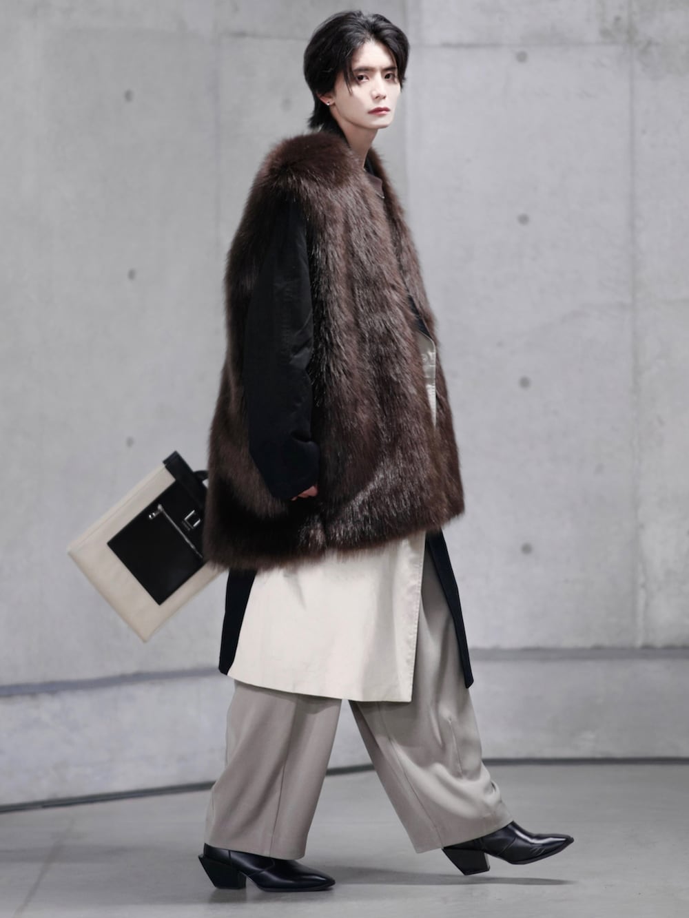 ベージュ系のトレンチコート、ブラック系のブーツ、ベージュ系のトートバッグを着用したメンズの冬コーディネートの2枚目の写真