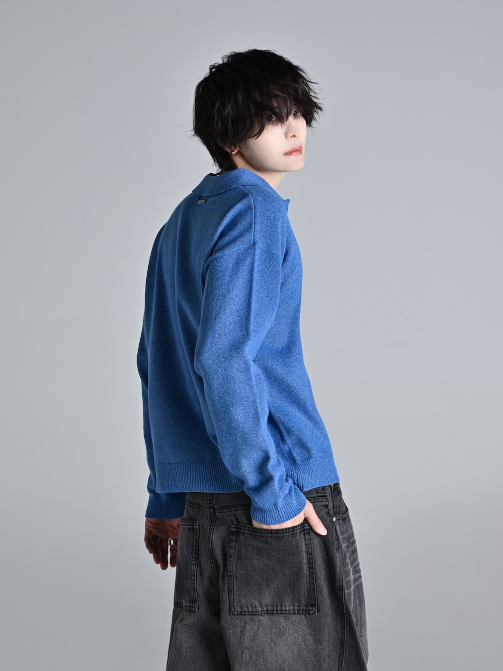 ブルー系のデニムパンツ、ブラック系のショルダーバッグ、ホワイト系のスニーカーを着用したメンズの冬コーディネートの3枚目の写真