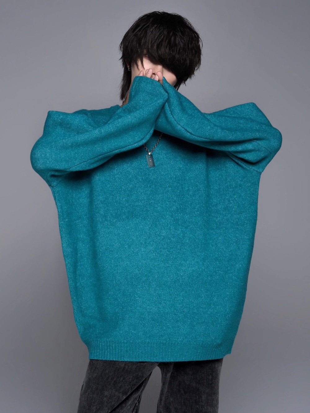 ブラック系のデニムパンツ、ブラック系のスニーカー、グリーン系のニット/セーターを着用したメンズの秋コーディネートの2枚目の写真