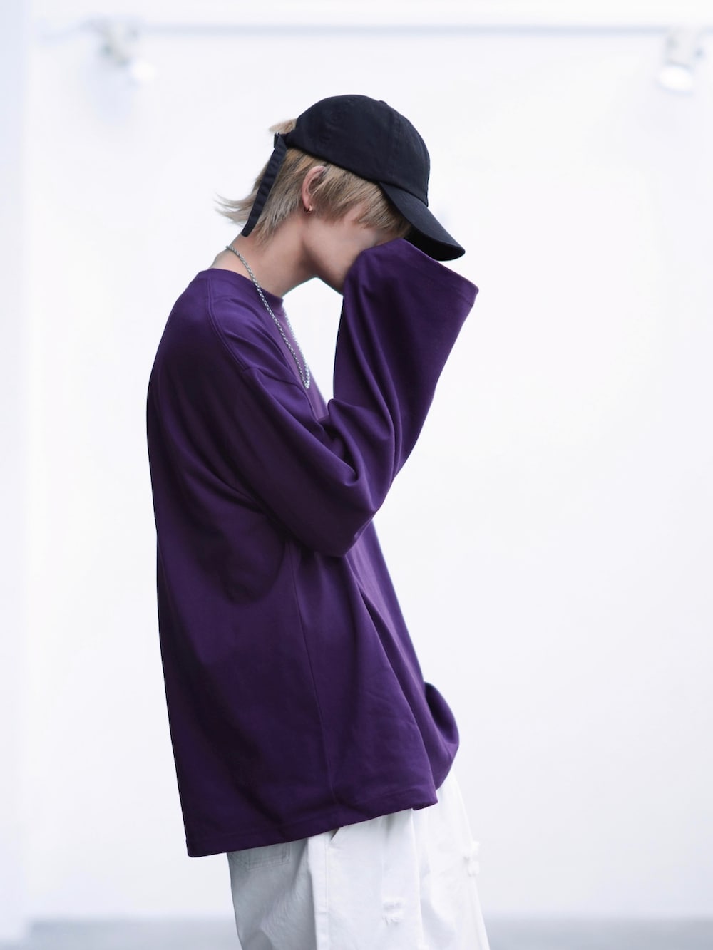 ブラック系のスニーカー、パープル系のTシャツ/カットソー、ホワイト系のデニムパンツを着用したメンズの春コーディネートの3枚目の写真