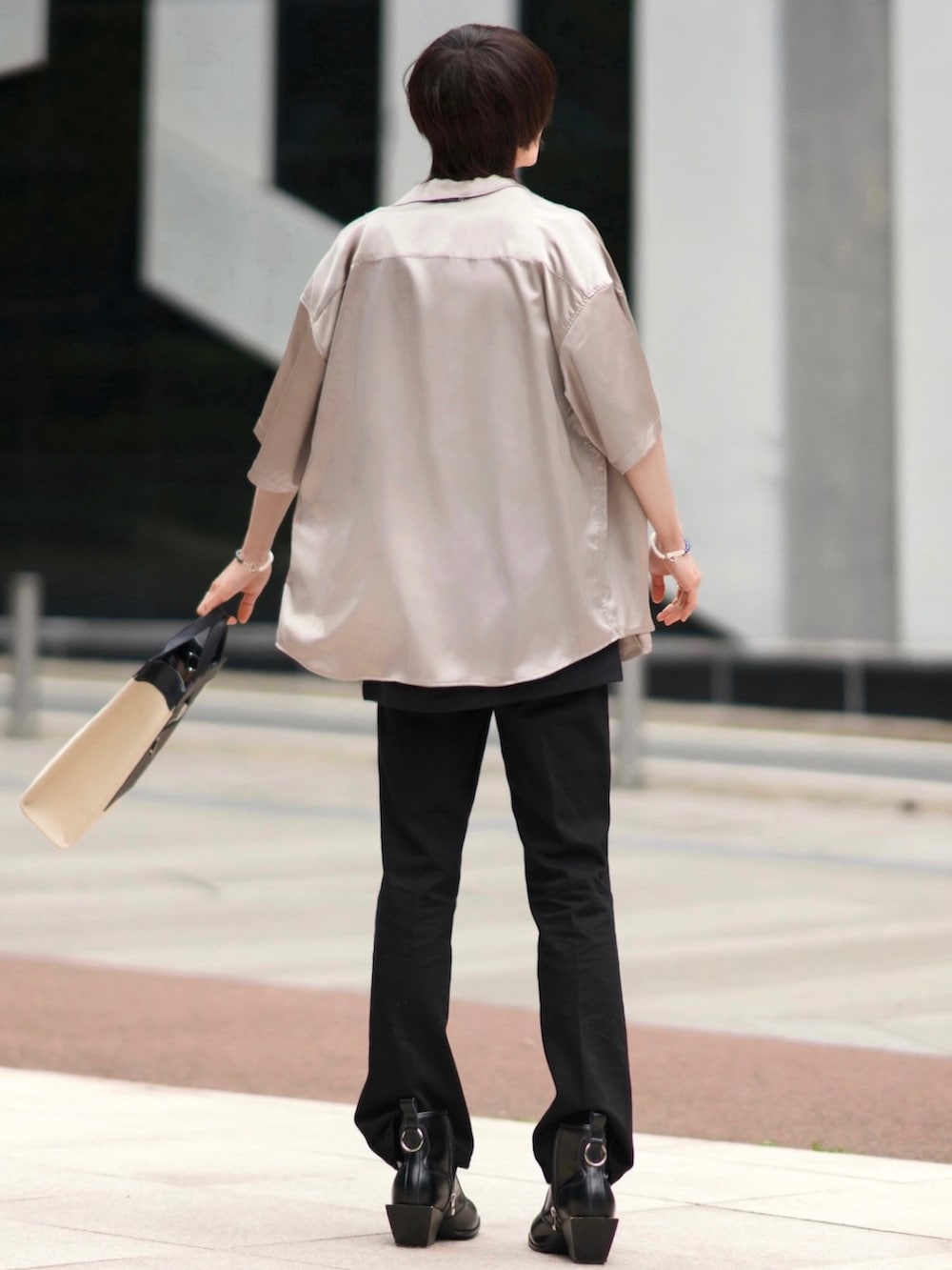 ブラック系のデニムパンツ、ベージュ系のトートバッグ、ブラック系のブーツを着用したメンズの春コーディネートの2枚目の写真