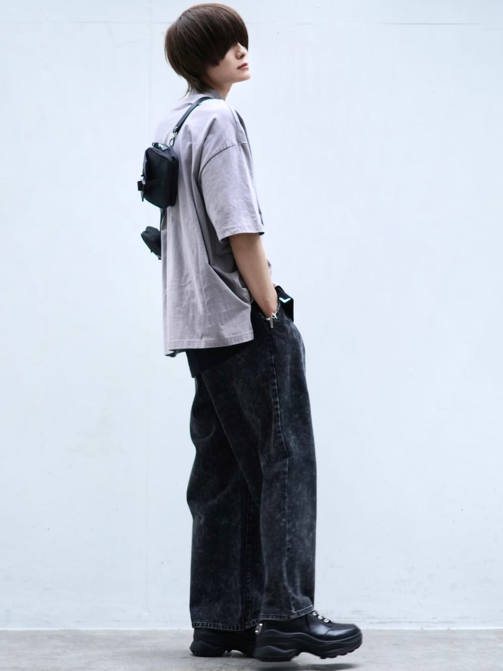 ブラック系のデニムパンツ、ブラック系のスニーカー、ブラック系のショルダーバッグを着用したメンズの春コーディネートの3枚目の写真