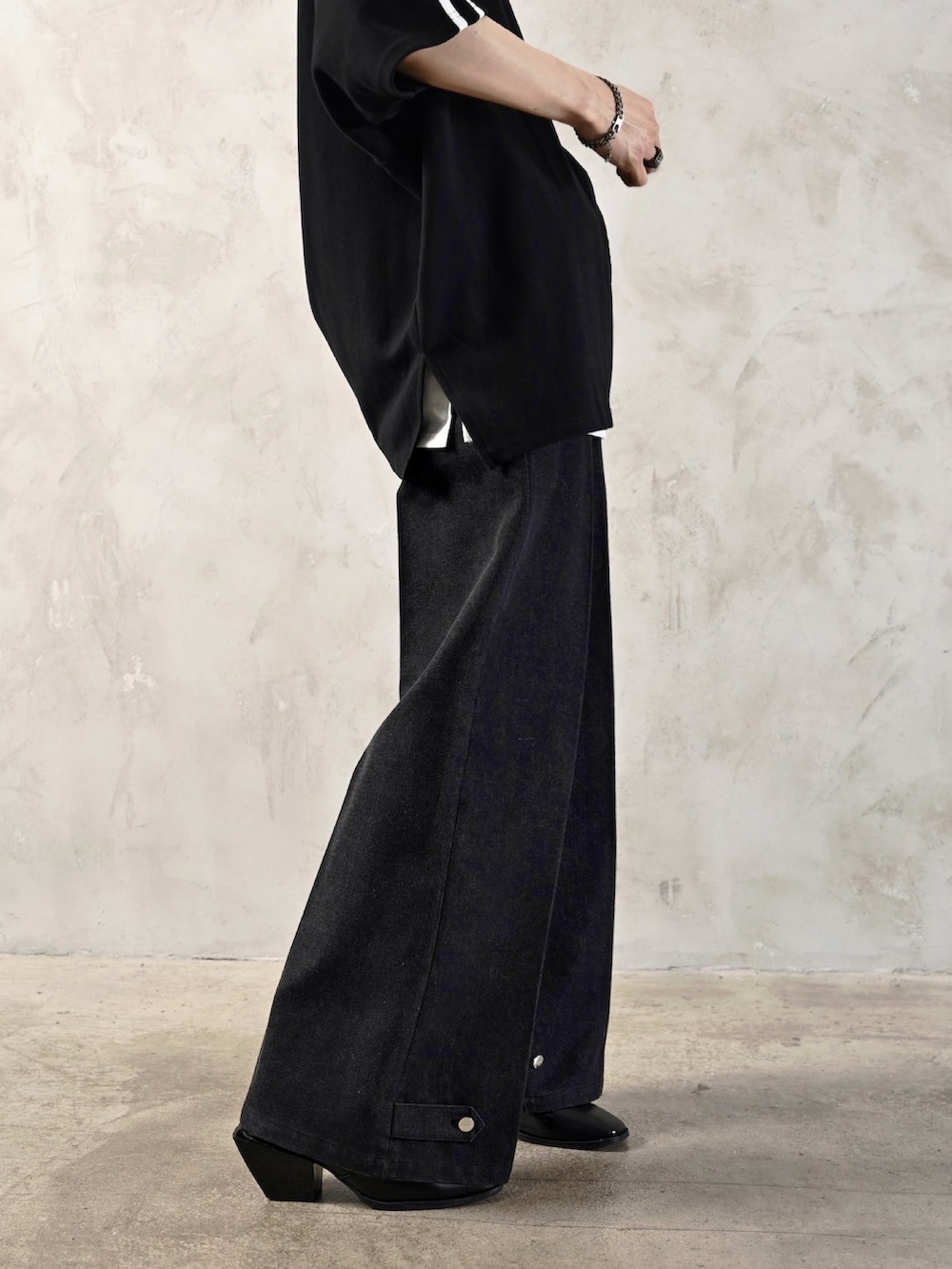 ホワイト系のタンクトップ、ブラック系のブーツ、ブラック系のショルダーバッグを着用したメンズの春コーディネートの5枚目の写真