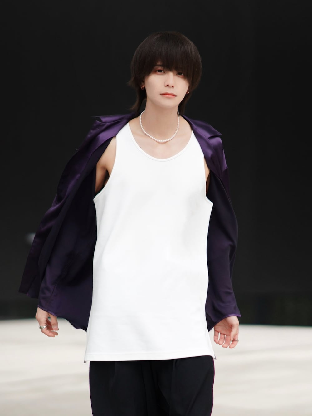 ブラック系のスラックス、ブラック系のブーツ、ベージュ系のトートバッグを着用したメンズの春コーディネートの3枚目の写真