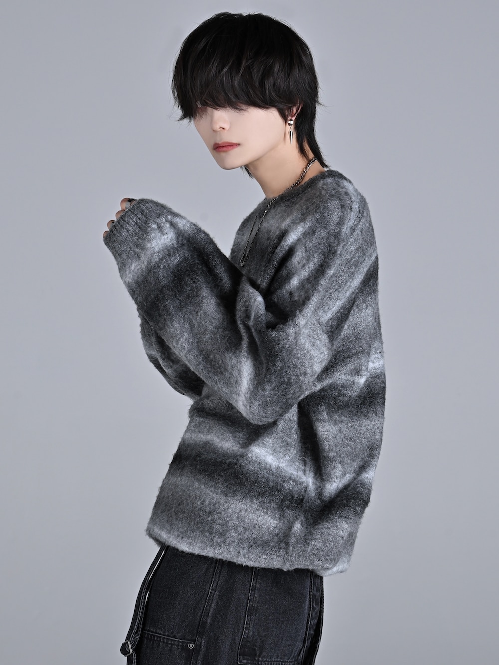 ブラック系のニット/セーター、ブラック系のデニムパンツ、ホワイト系のスニーカーを着用したメンズの秋コーディネートの3枚目の写真