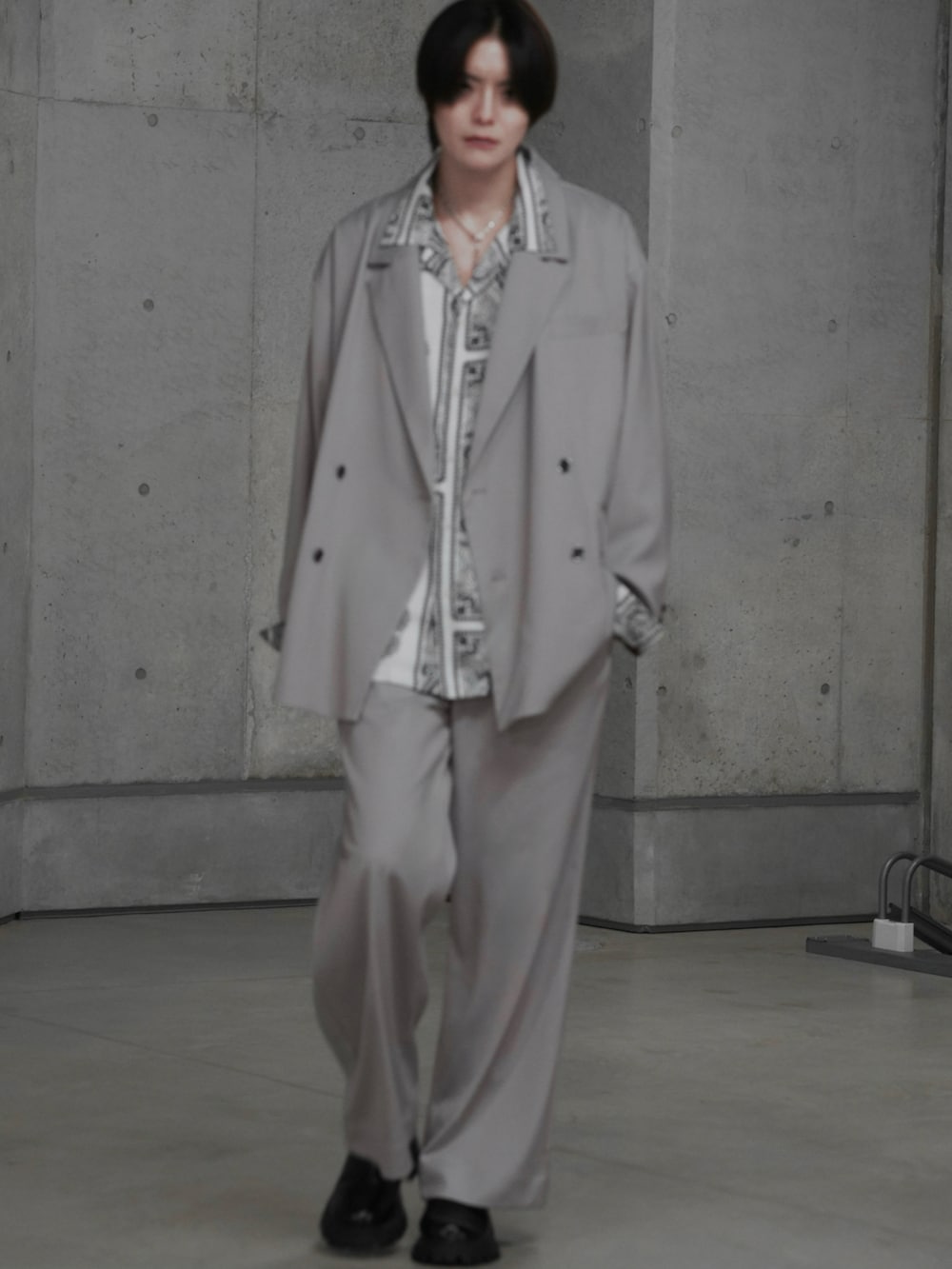 ブラック系のブーツ、グレー系のテーラードジャケット、グレー系のスラックスを着用したメンズの冬コーディネートの2枚目の写真