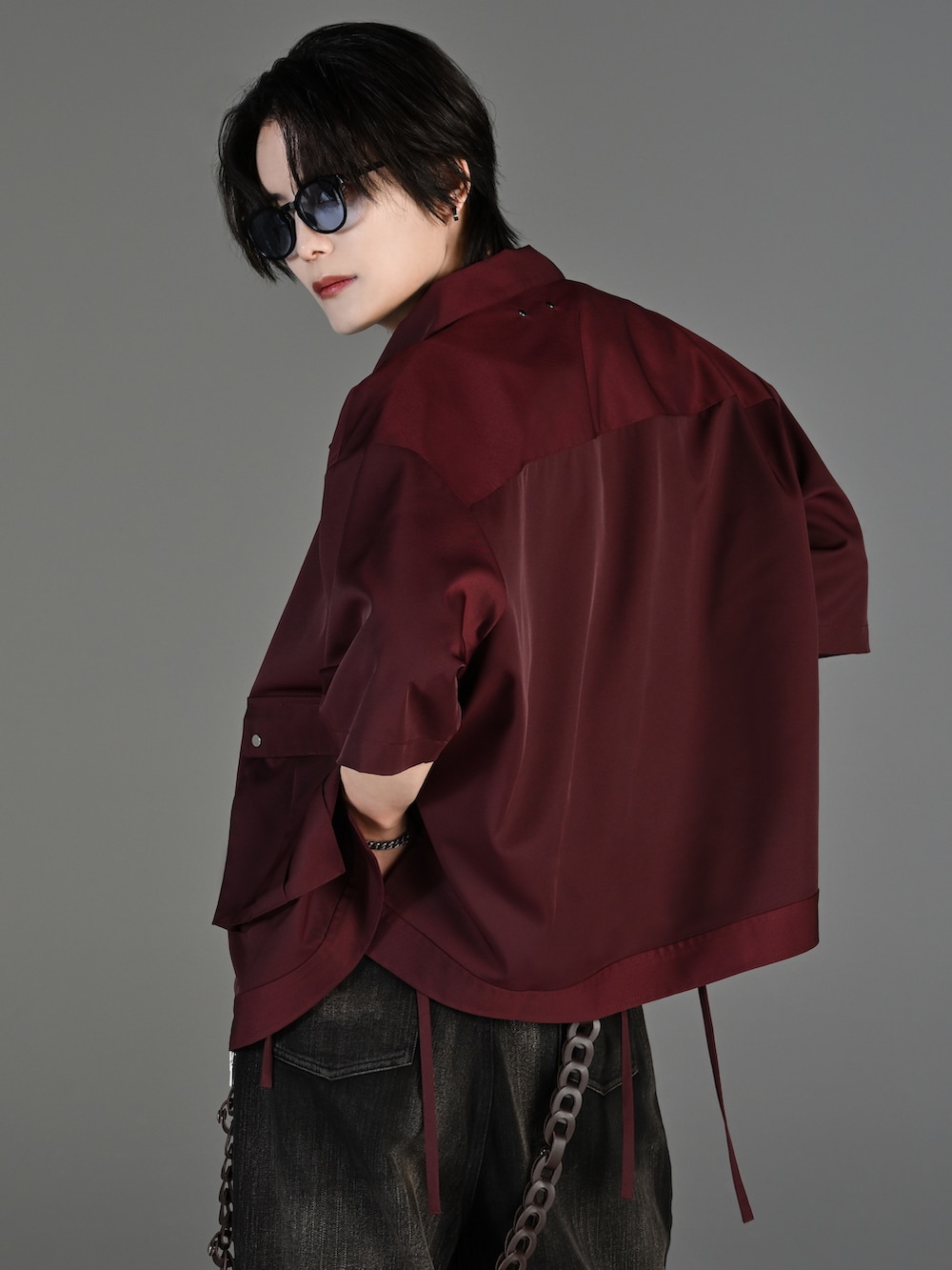 ブラック系のデニムパンツ、ブラック系のブーツ、レッド系のタンクトップを着用したメンズの春コーディネートの5枚目の写真