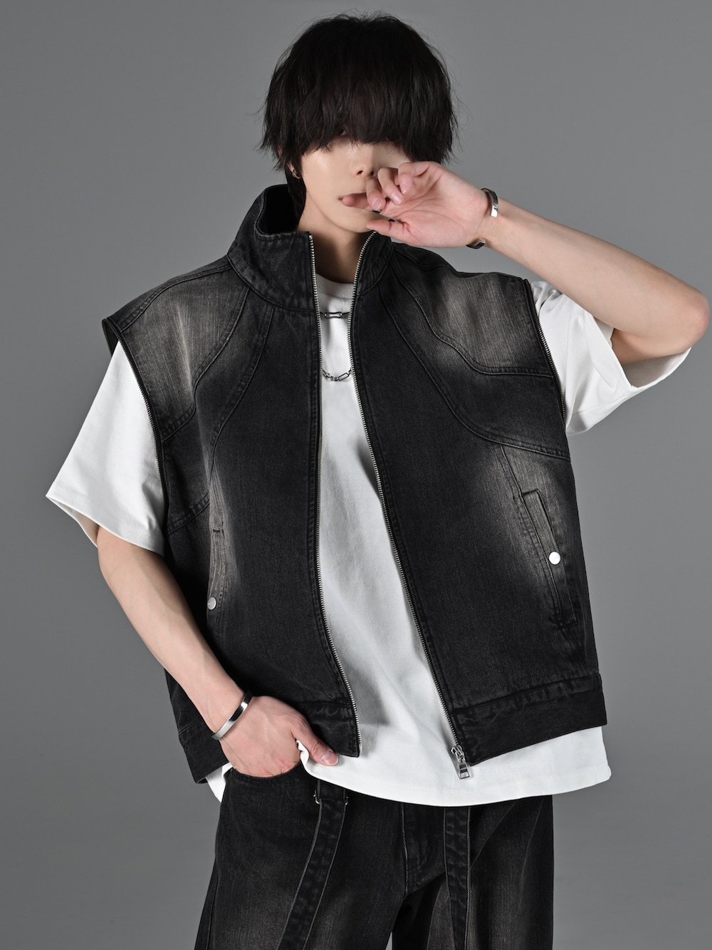 グレー系のタンクトップ、ブラック系のデニムパンツ、ホワイト系のスニーカーを着用したメンズの冬コーディネートの4枚目の写真