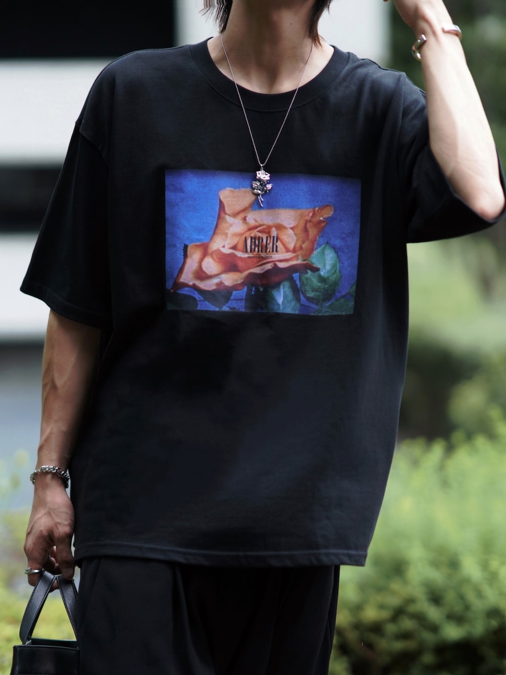 ブラック系のトートバッグ、ブラック系のスラックス、ブラック系のブーツを着用したメンズの夏コーディネートの3枚目の写真