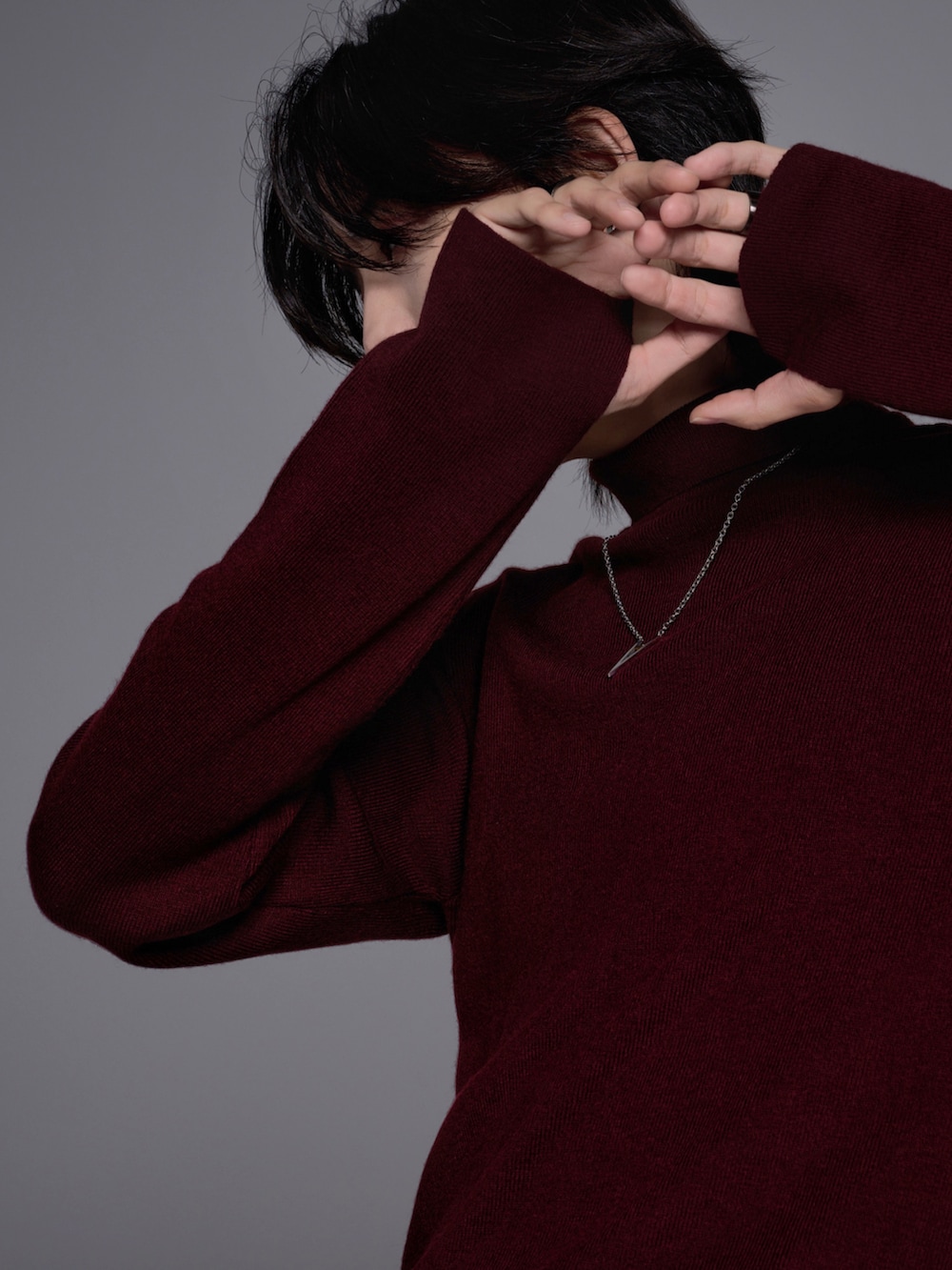 ブラック系のスニーカー、ブラック系のニット/セーター、グレー系のデニムパンツを着用したメンズの秋コーディネートの3枚目の写真