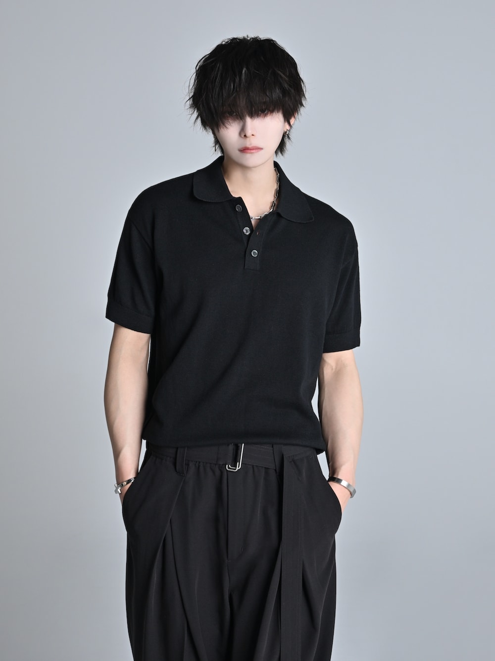 ブラック系のスラックス、ブラック系のポロシャツ、ブラック系のショルダーバッグを着用したメンズの春コーディネートの2枚目の写真