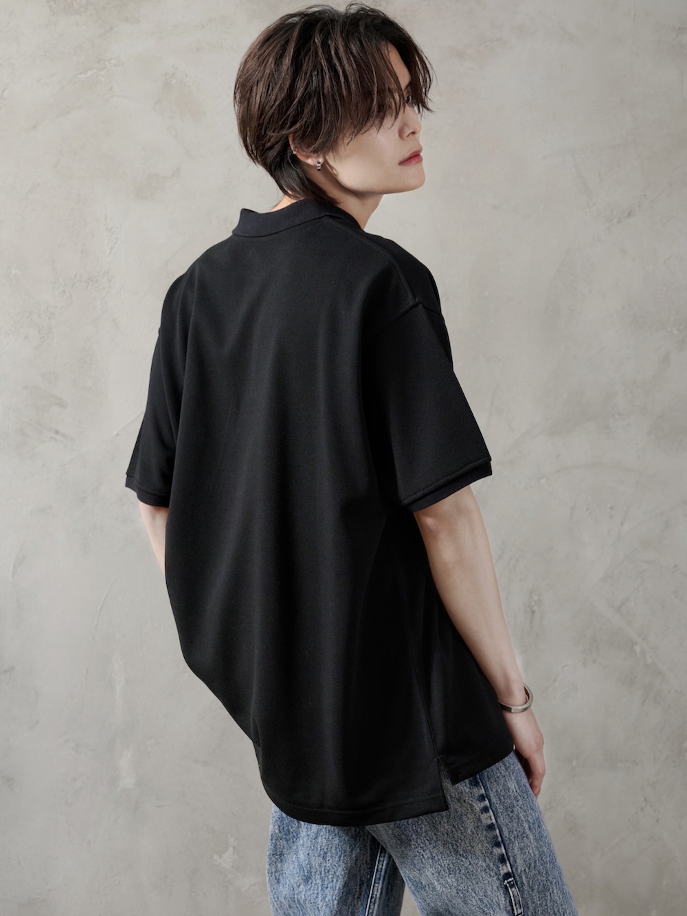 ブルー系のデニムパンツ、ブラック系のブーツ、ブラック系のポロシャツを着用したメンズの春コーディネートの5枚目の写真