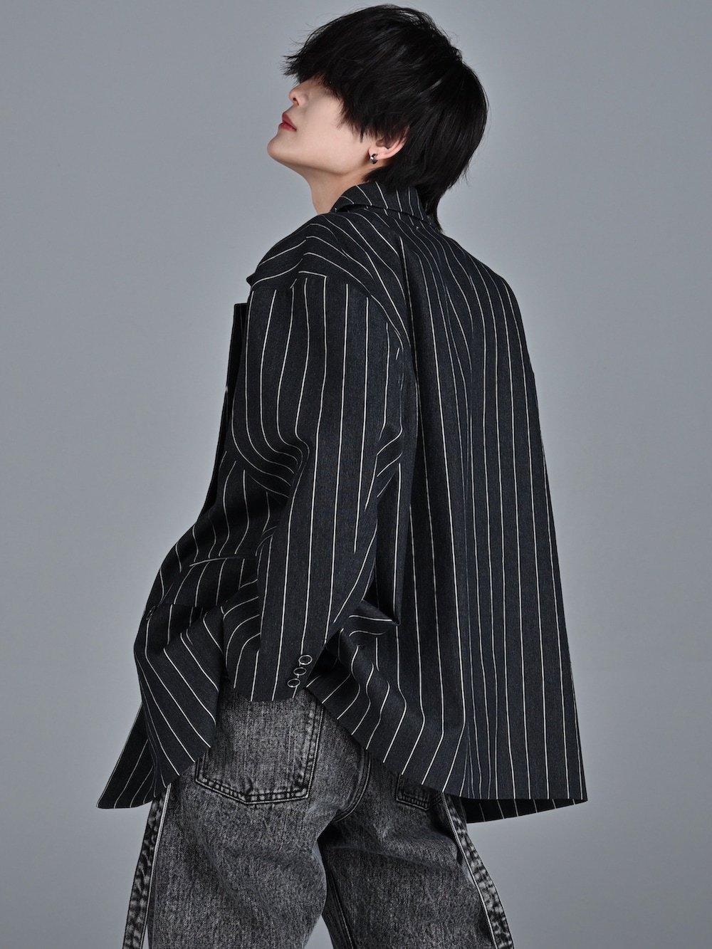 レッド系のタンクトップ、ブラック系のテーラードジャケット、ブラック系のデニムパンツを着用したメンズの冬コーディネートの4枚目の写真