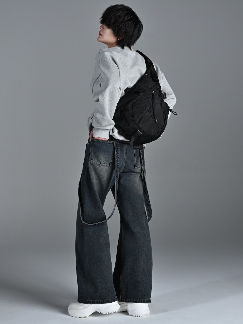 ホワイト系のスニーカー、グレー系のスウェット、ブルー系のデニムパンツを着用したメンズの冬コーディネートの2枚目の写真