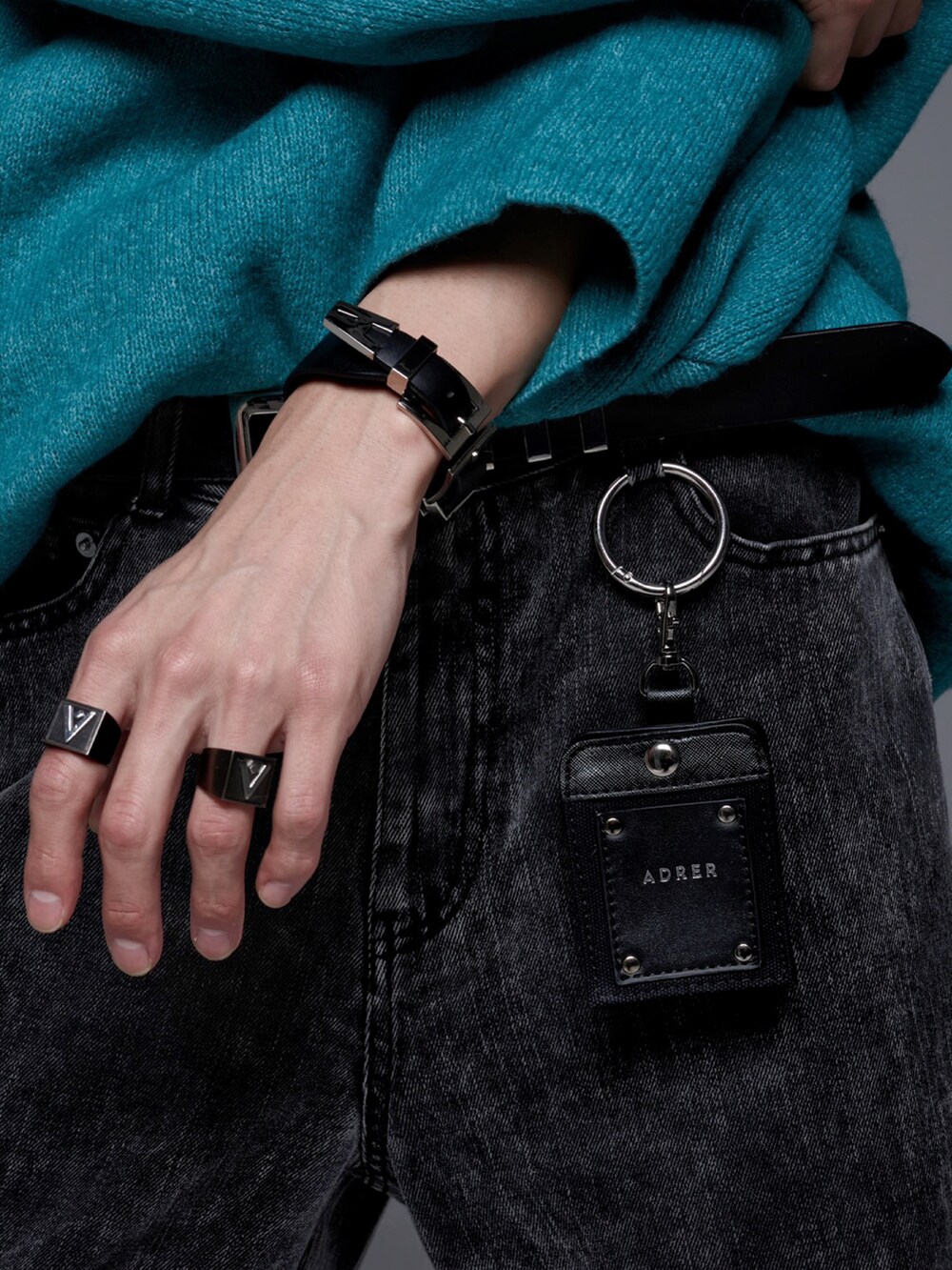 ブラック系のデニムパンツ、ブラック系のスニーカー、グリーン系のニット/セーターを着用したメンズの秋コーディネートの4枚目の写真