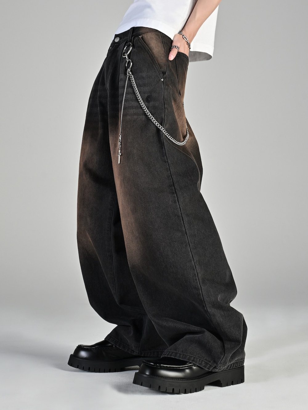 ブラック系のスニーカー、ブラウン系のニット/セーター、ブラック系のデニムパンツを着用したメンズの秋コーディネートの5枚目の写真