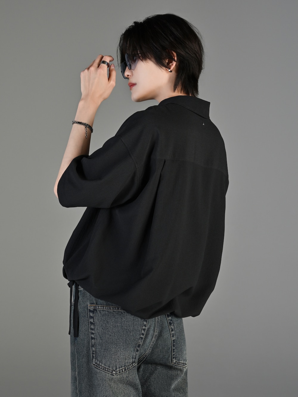 ブルー系のデニムパンツ、ブラック系のブーツ、ブラック系のショルダーバッグを着用したメンズの春コーディネートの4枚目の写真