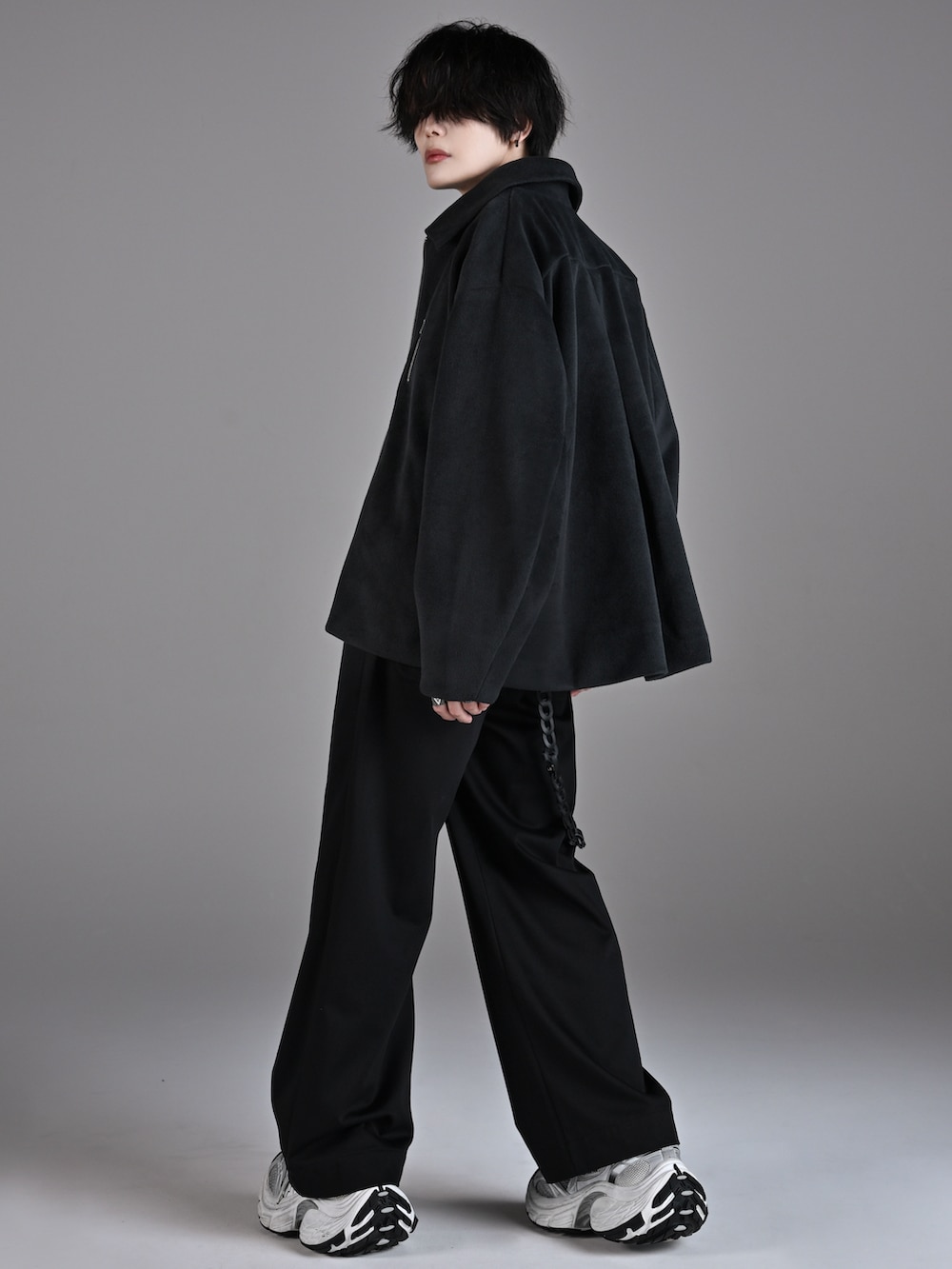 ブラック系のスラックス、ホワイト系のスニーカー、グレー系のブルゾンを着用したメンズの秋コーディネートの2枚目の写真