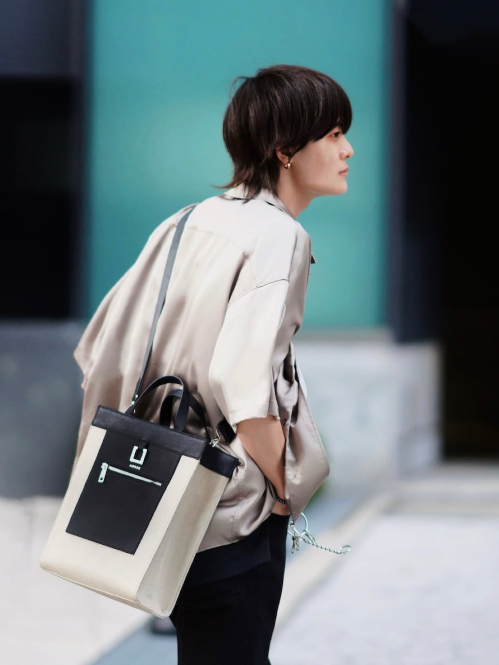 ブラック系のデニムパンツ、ベージュ系のトートバッグ、ブラック系のブーツを着用したメンズの春コーディネートの3枚目の写真