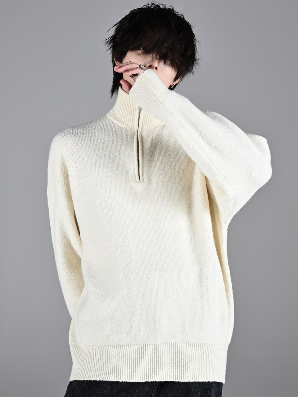 ホワイト系のスニーカー、ホワイト系のニット/セーター、ブラック系のデニムパンツを着用したメンズの秋コーディネートの2枚目の写真