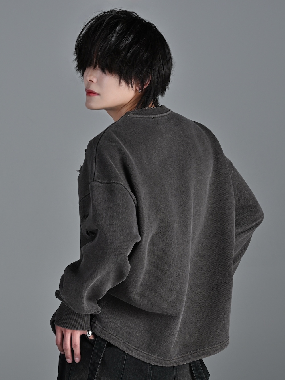 ブラウン系のスウェット、ブラック系のデニムパンツ、ホワイト系のスニーカーを着用したメンズの冬コーディネートの4枚目の写真