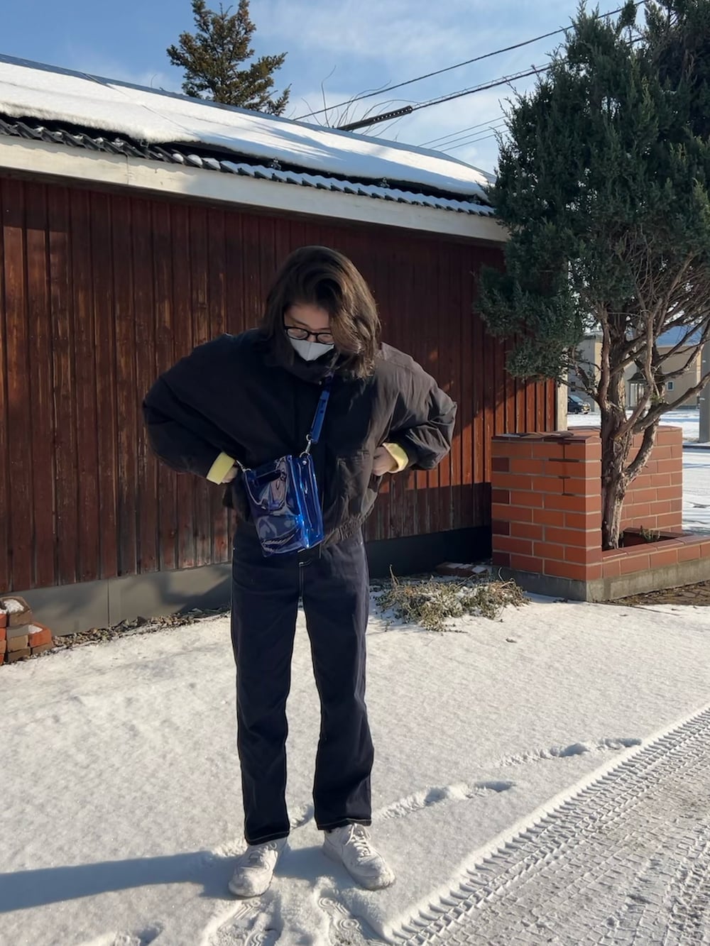 ホワイト系のスニーカー、ブラック系のパンツ、ブルー系のショルダーバッグを着用したレディースの冬コーディネートの2枚目の写真