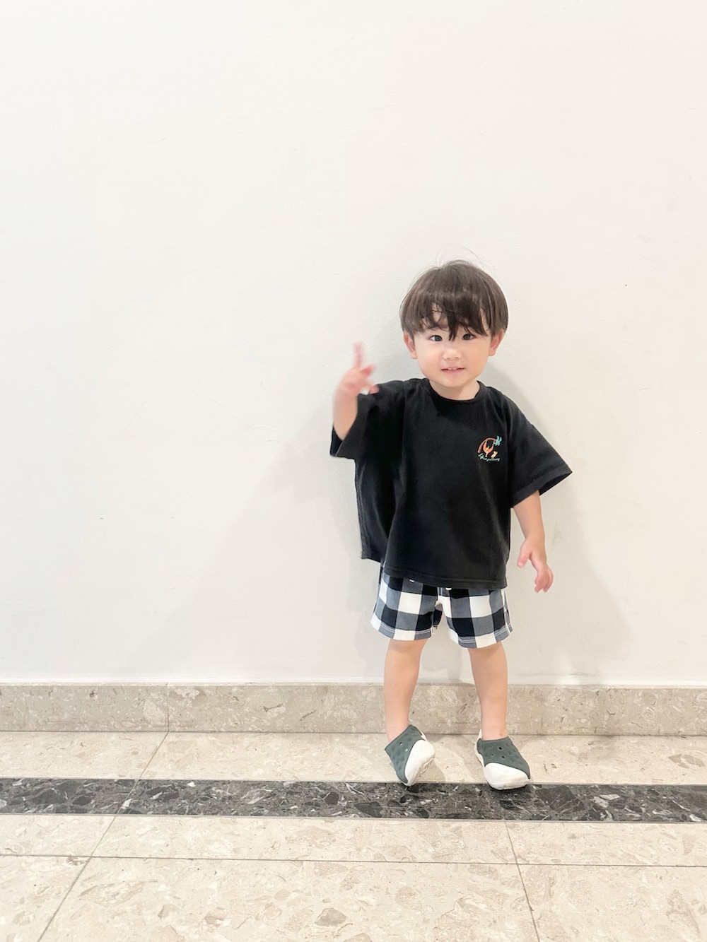 ブラック系のサンダル、ブラック系のTシャツ/カットソー、ホワイト系の水着を着用したキッズの春コーディネートの2枚目の写真