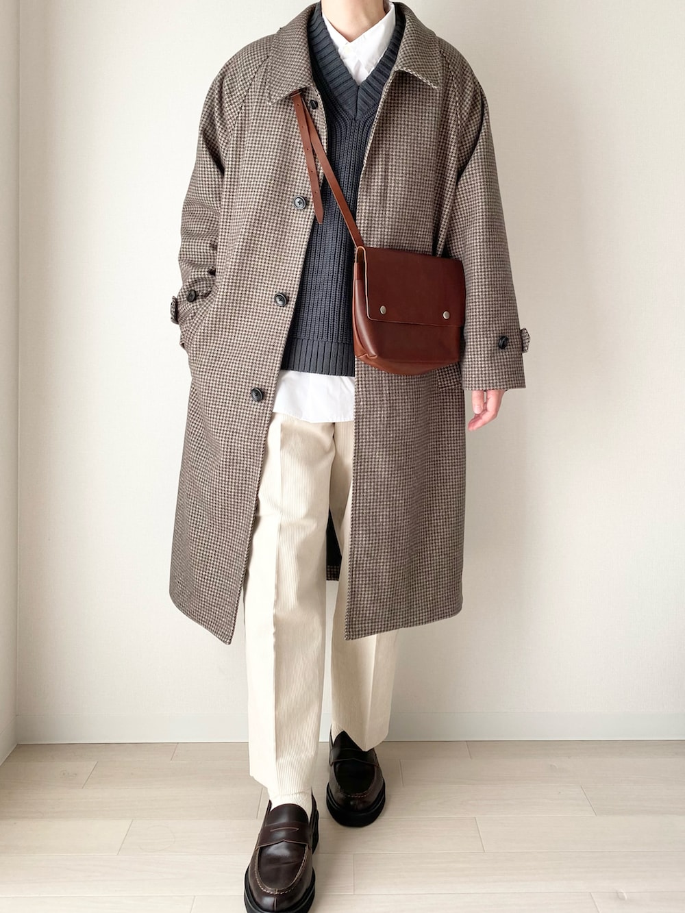 ブラウン系のステンカラーコート、グリーン系のニット/セーター、ホワイト系のその他パンツを着用したメンズの冬コーディネートの2枚目の写真
