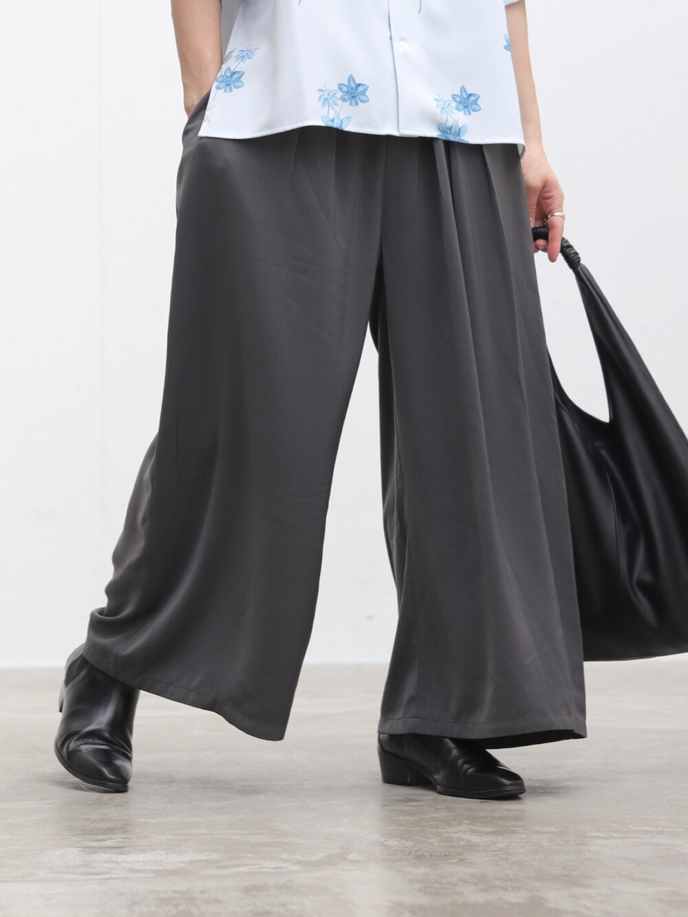 グレー系のスカート、ブラック系のブーツ、ブラック系のトートバッグを着用したメンズの夏コーディネートの3枚目の写真