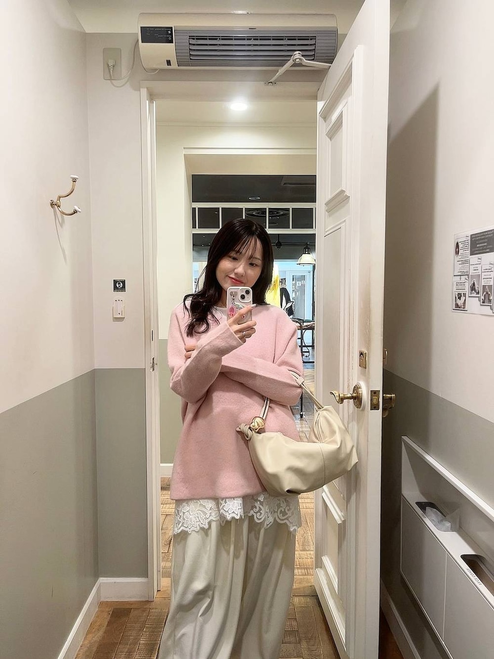 ピンク系のニット/セーター、ホワイト系のスラックス、ホワイト系のキャミソールを着用したレディースの冬コーディネートの2枚目の写真