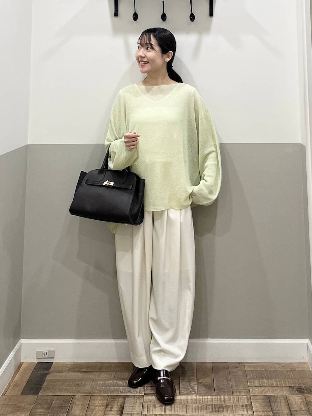 ホワイト系のスラックス、ブラウン系のショルダーバッグ、グリーン系のニット/セーターを着用したレディースの春コーディネートの4枚目の写真