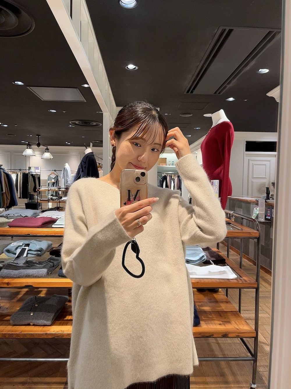 ブラウン系のステンカラーコート、ホワイト系のニット/セーター、ブラウン系のスカートを着用したレディースの秋コーディネートの3枚目の写真