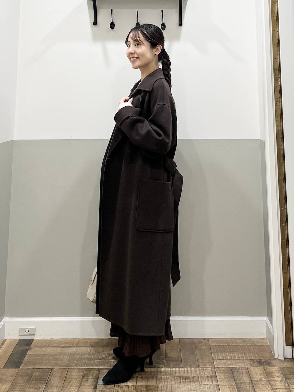 ブラウン系のステンカラーコート、ホワイト系のニット/セーター、ブラウン系のスカートを着用したレディースの秋コーディネートの4枚目の写真