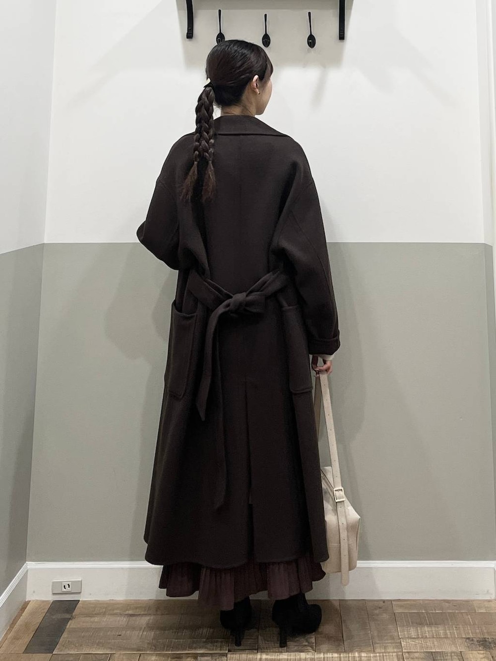 ブラウン系のステンカラーコート、ホワイト系のニット/セーター、ブラウン系のスカートを着用したレディースの秋コーディネートの6枚目の写真