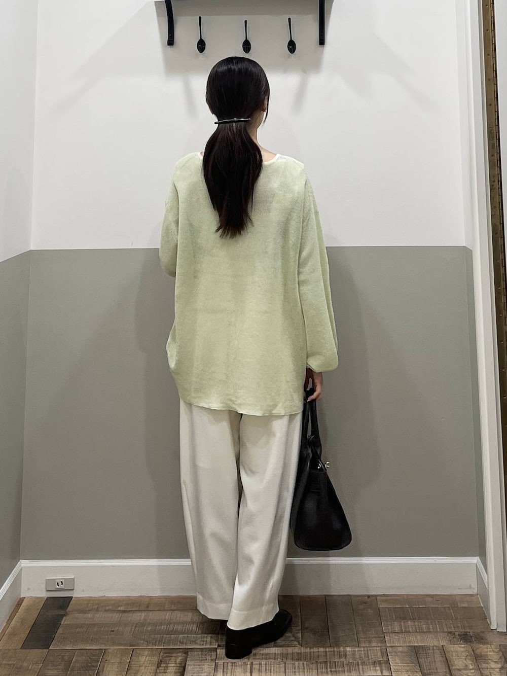 ホワイト系のスラックス、ブラウン系のショルダーバッグ、グリーン系のニット/セーターを着用したレディースの春コーディネートの7枚目の写真